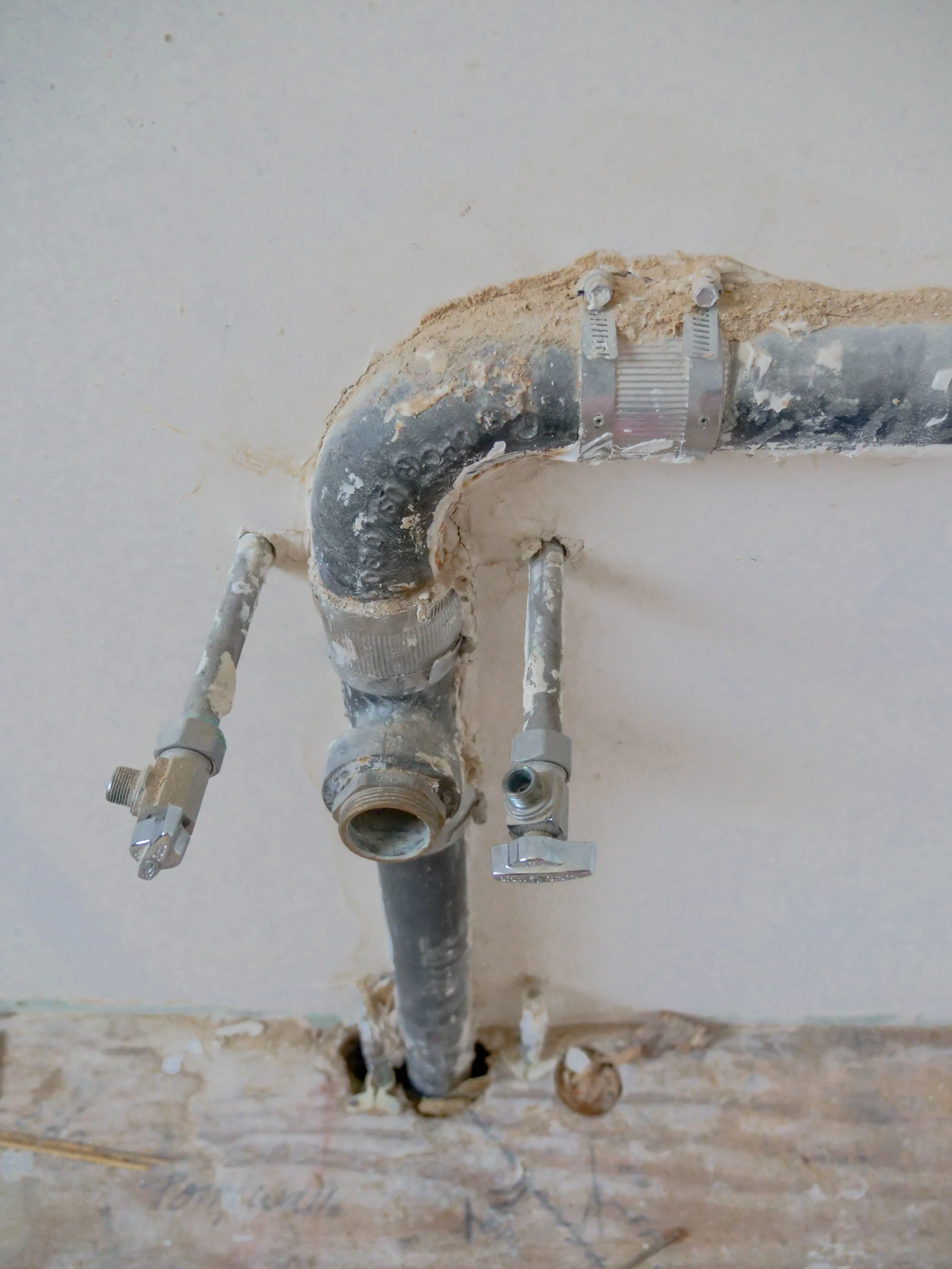 Exposed plumbing pipework running along a wall