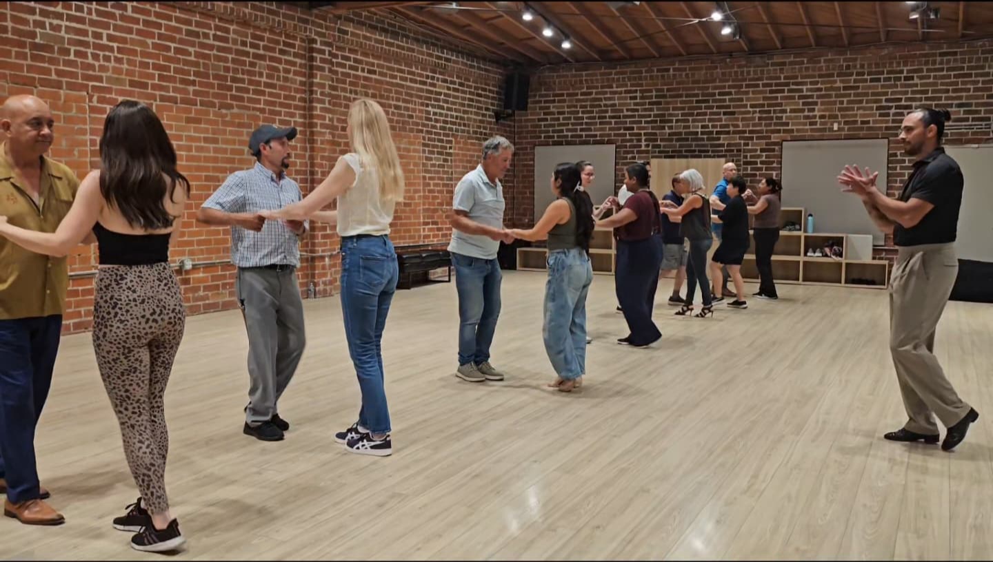 Dance couple performing salsa under warm stage lighting