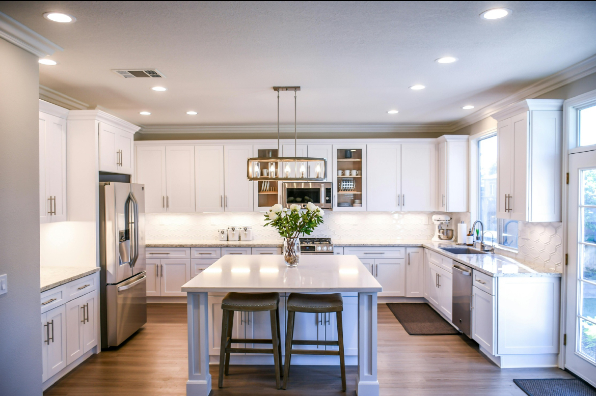 Modern white kitchen renovation in Northern Virginia showcasing a large center island, recessed lighting, shaker cabinets, and stainless steel appliances.
