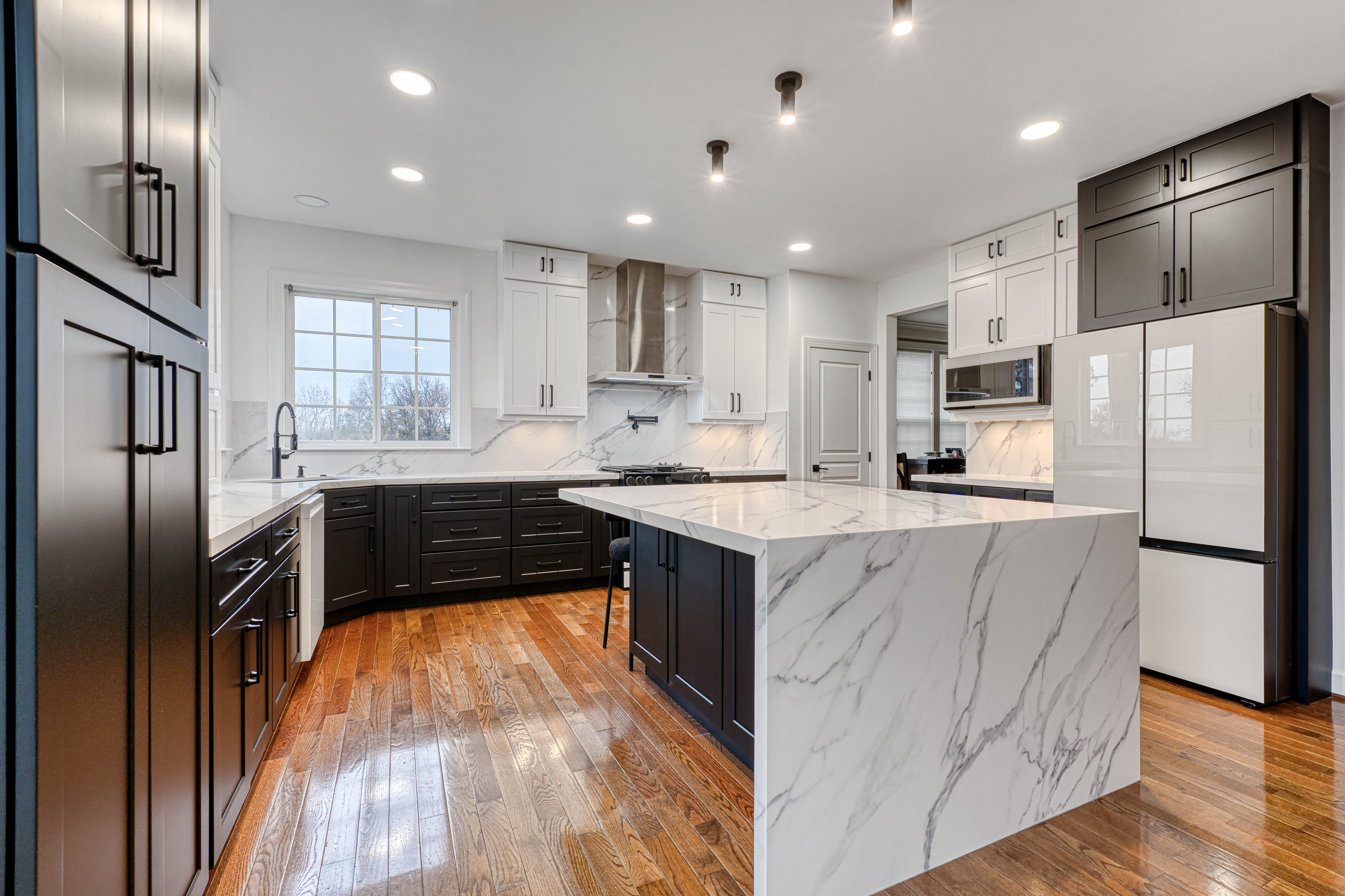 Contemporary kitchen design-build project in Chantilly, VA, featuring black lower cabinets, white upper cabinets, and a massive marble waterfall island.