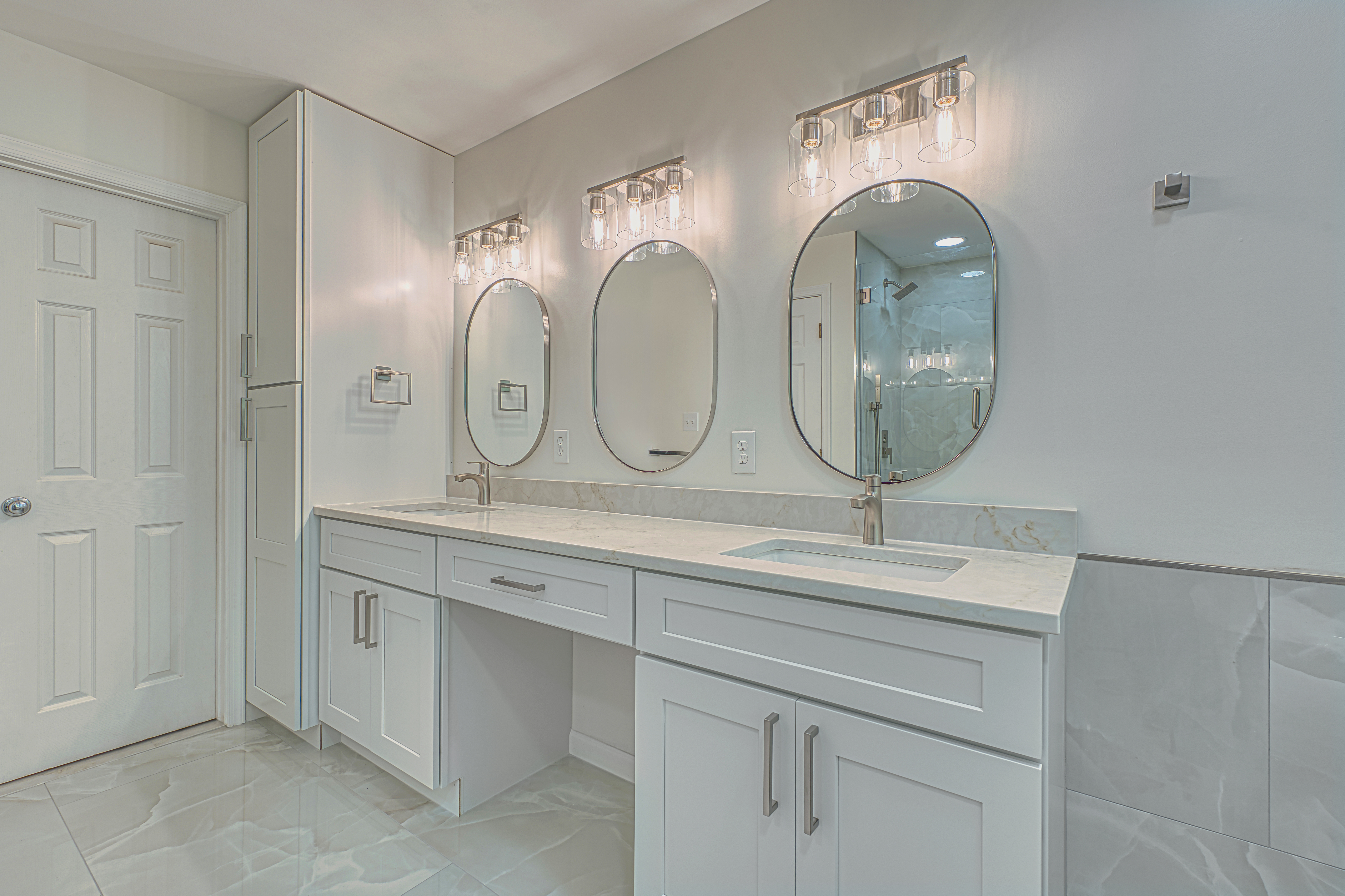 Custom white bathroom cabinetry and marble-look tile flooring from a professional home renovation in the Chantilly area.