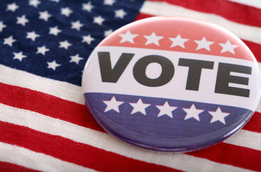 “Vote” button displayed on an American flag, representing civic participation and voting.