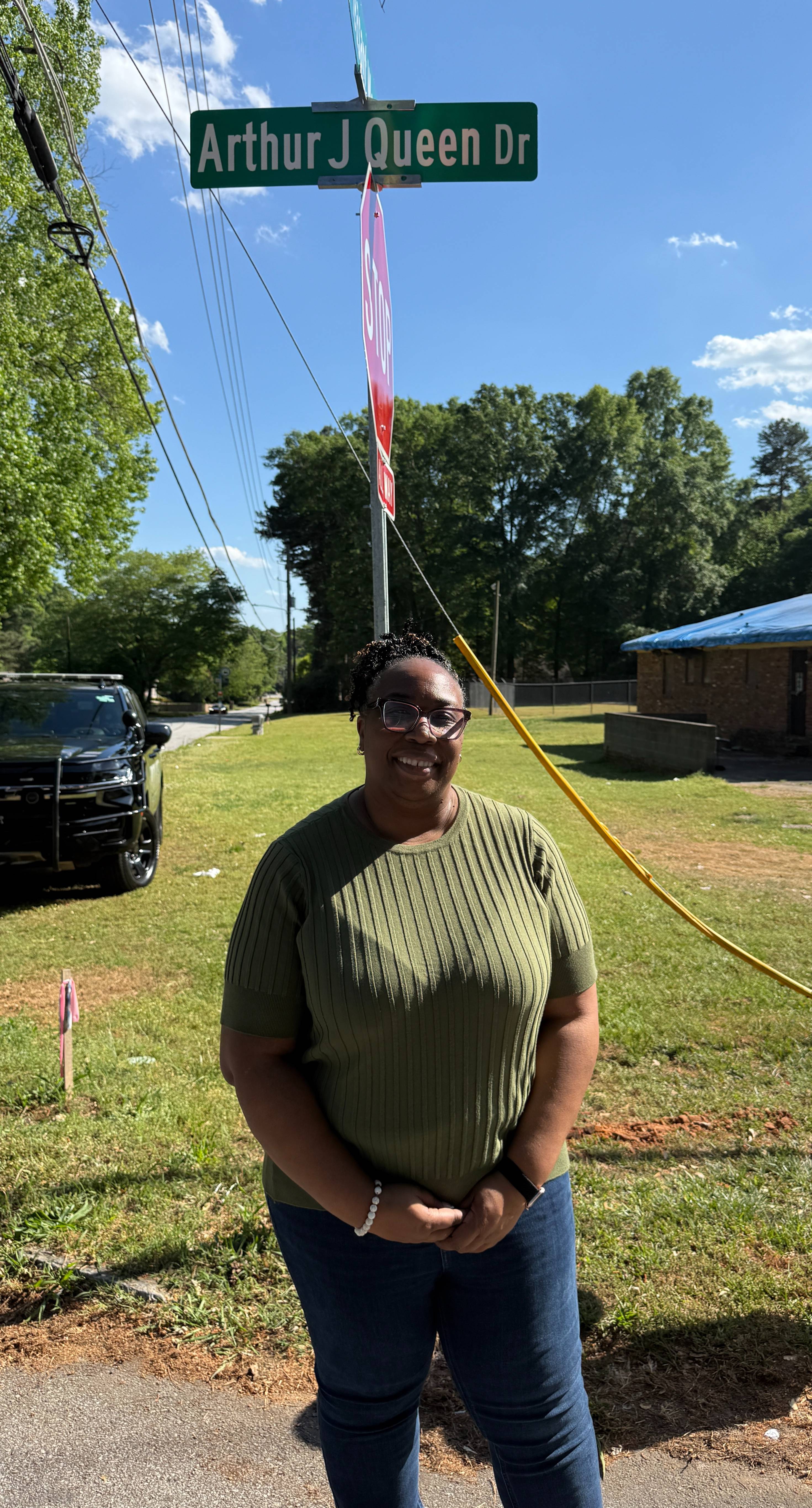Commissioner Chakira Johnson stands beneath the newly unveiled Arthur J. Queen Drive street sign following the renaming ceremony.