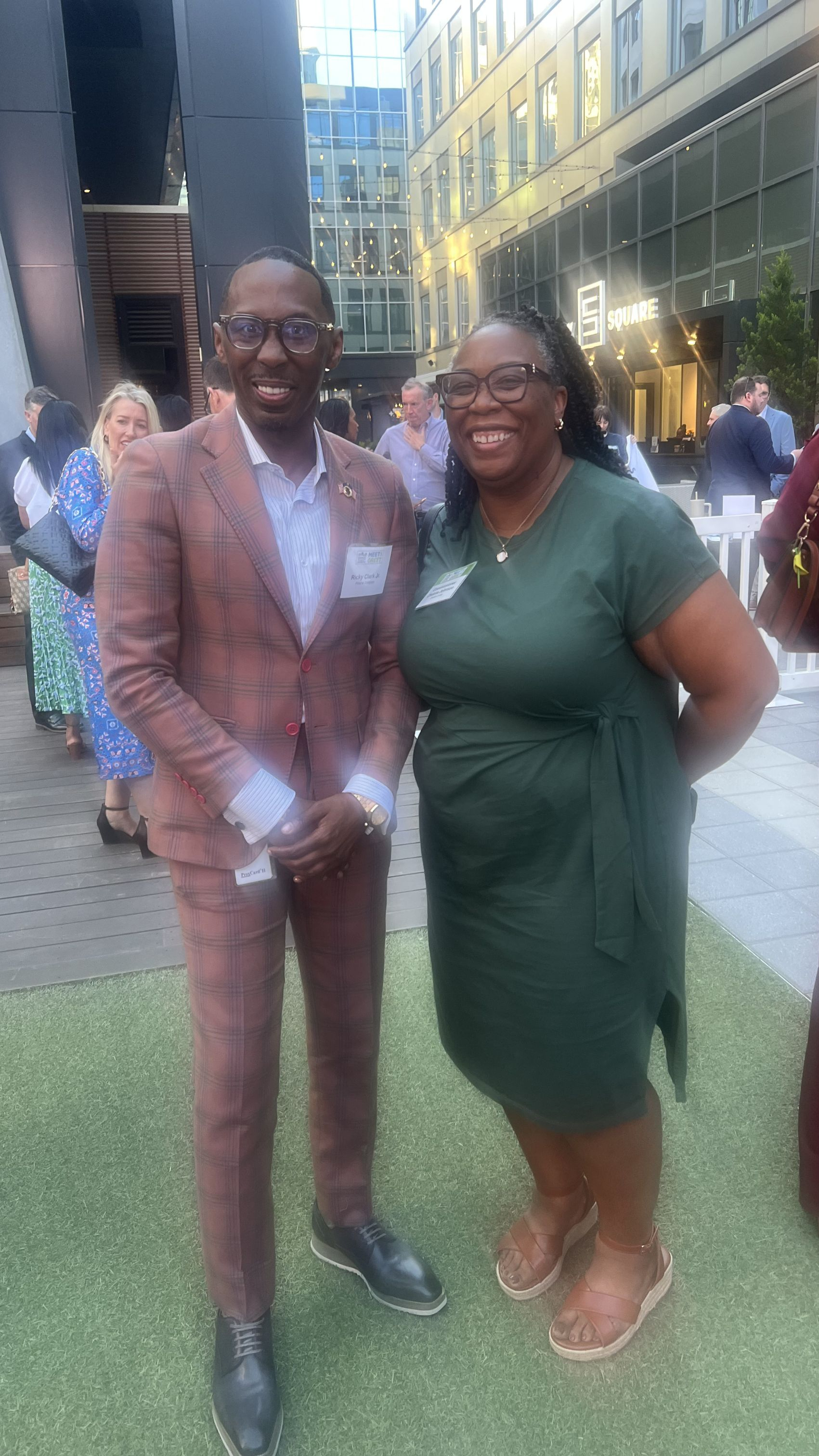 Presiding Officer Commissioner Chakira Johnson poses with Ricky L. Clark Jr. of Pond & Company during the 21st Annual Council for Quality Growth Meet & Greet event. The two stand outdoors in a modern courtyard surrounded by attendees networking during the evening event.