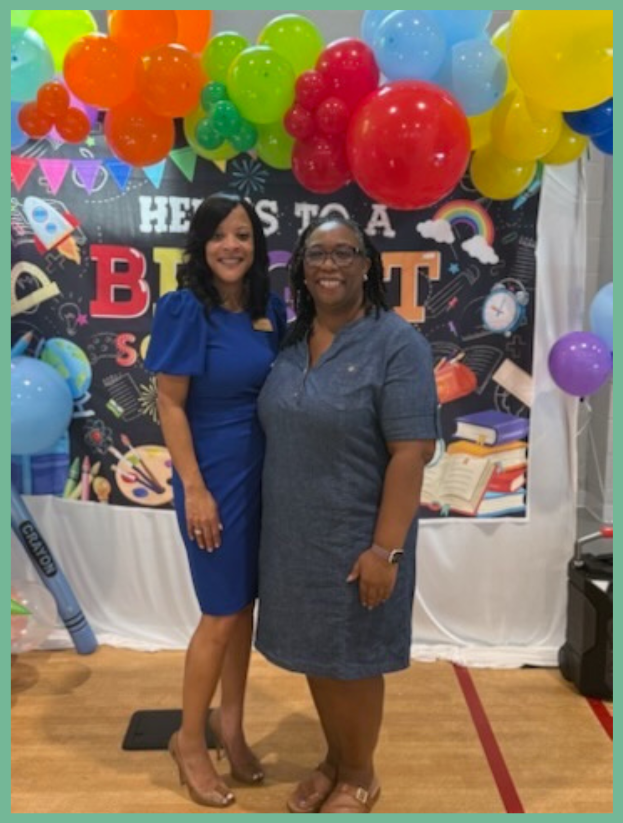 Presiding Officer Commissioner Chakira Johnson poses with Scottdale Early Learning CEO Dr. Leah Skinner in front of a colorful back-to-school display at the organization's Back-to-School Bash.
