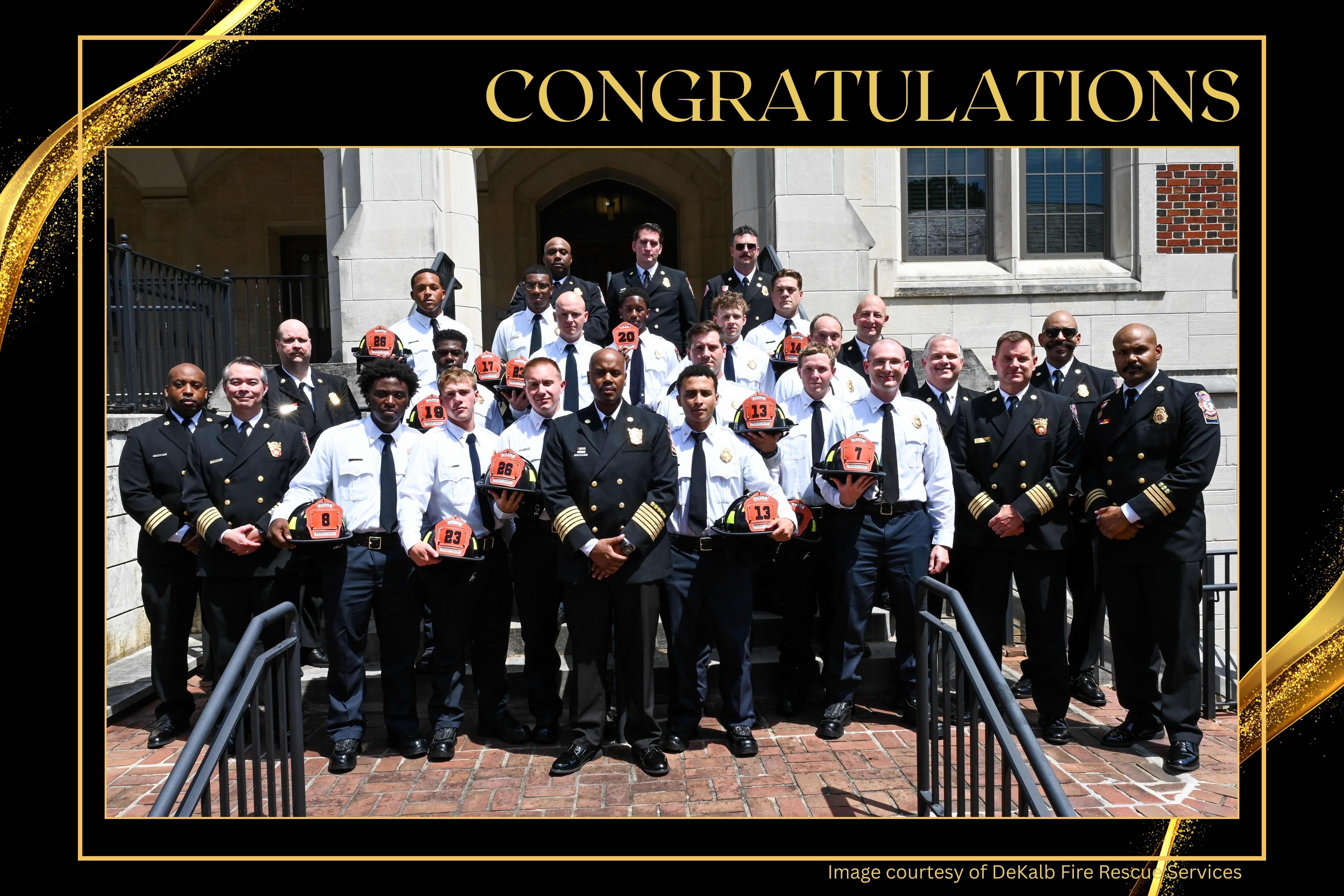 Group photo of DeKalb County Fire Rescue Class 1225 graduates and department leaders posed on the steps of a building after the graduation ceremony. Several graduates hold firefighter helmets marked with their station or recruit numbers. The image is framed in black and gold beneath the word “Congratulations.”