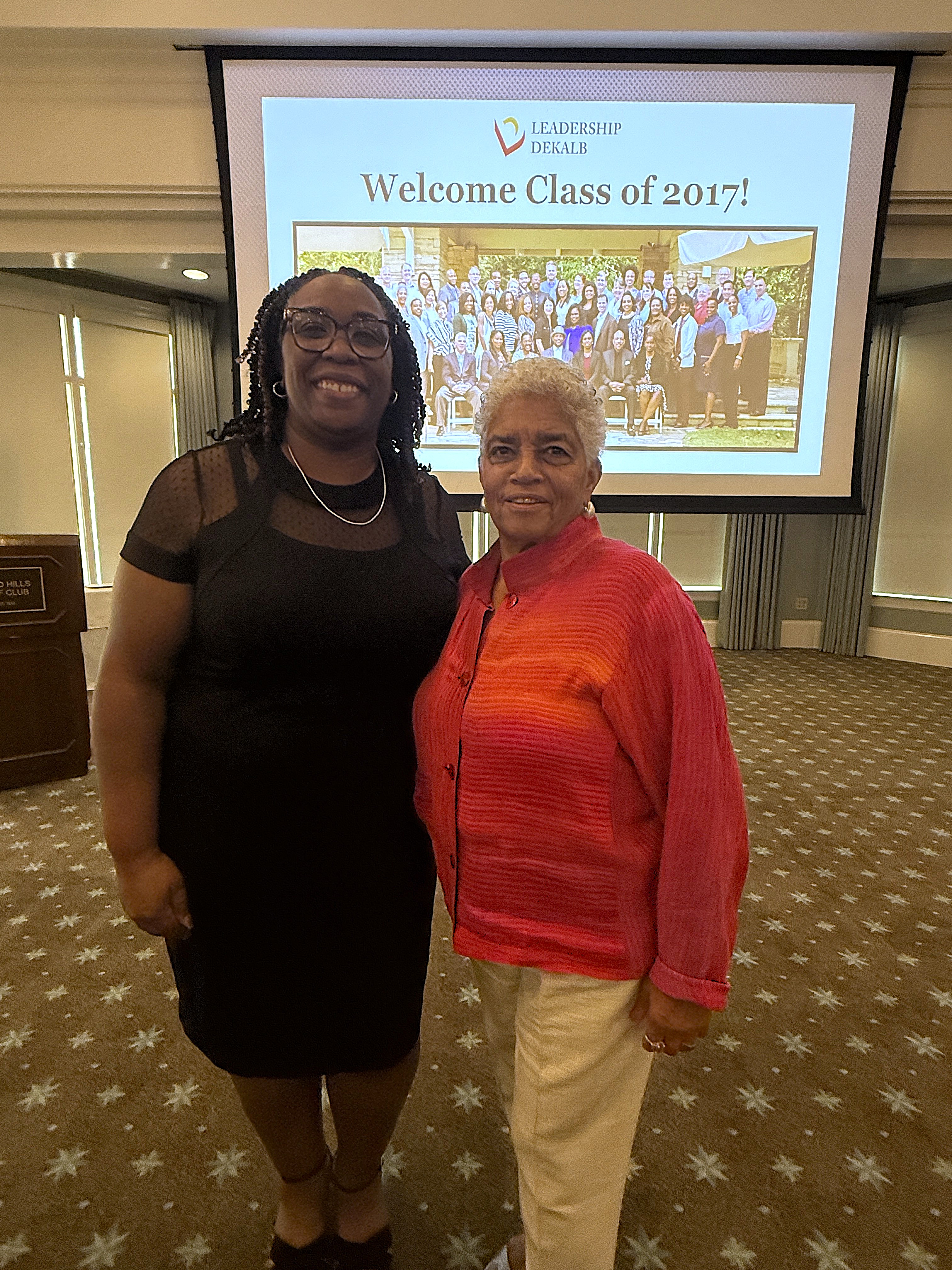 Presiding Officer Commissioner Chakira Johnson and former Atlanta Mayor Shirley Franklin smile together during Leadership DeKalb’s Annual Dinner, with a Leadership DeKalb presentation displayed behind them.