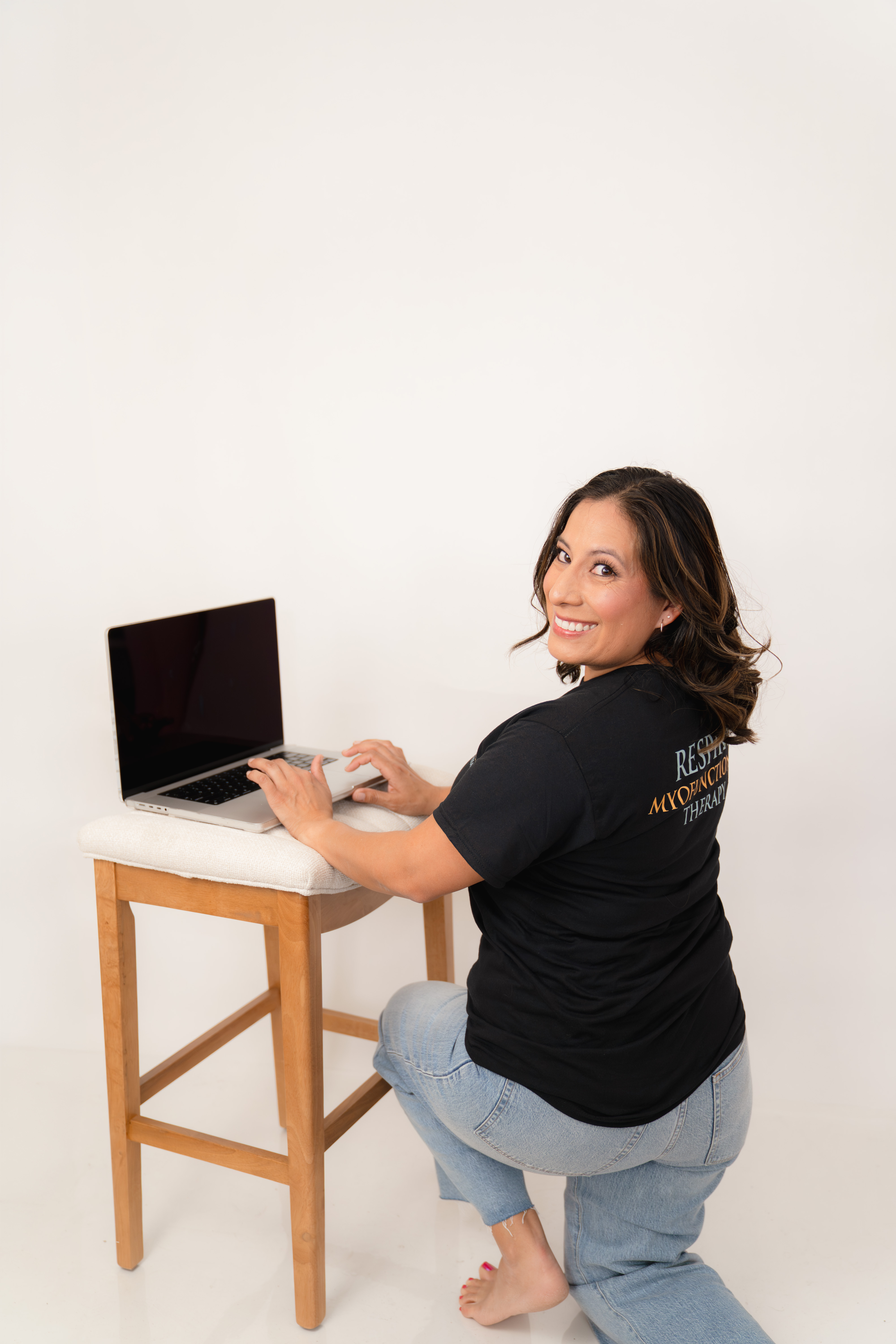 Stephanie smiling over her shoulder while setting up a laptop for a virtual therapy session