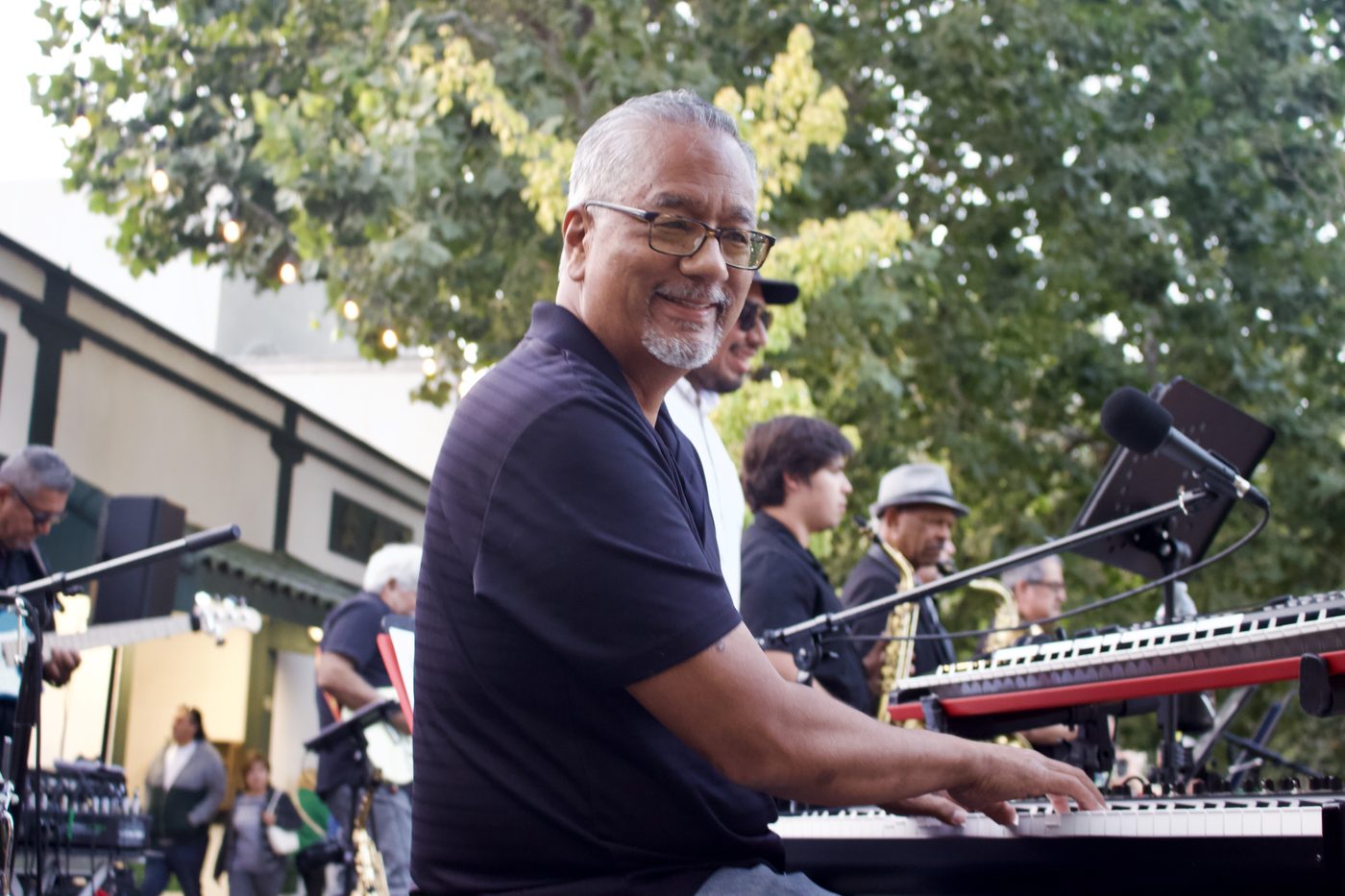 Bobby Valderrama smiling at the keyboard during a live outdoor performance