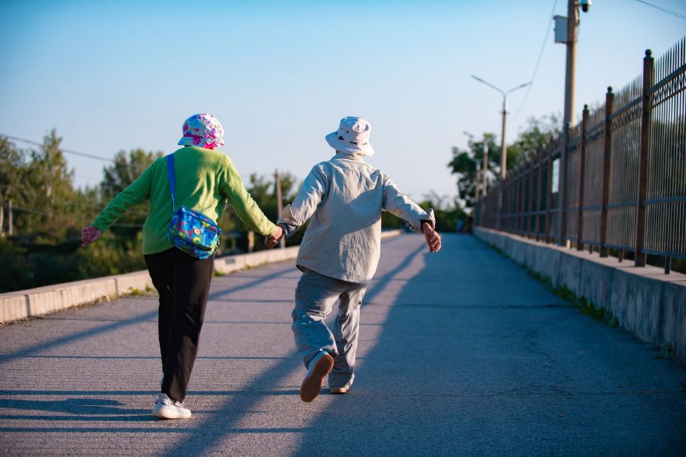 Older adult walking outdoors as gentle daily exercise Older adult walking outdoors as gentle daily exercise
