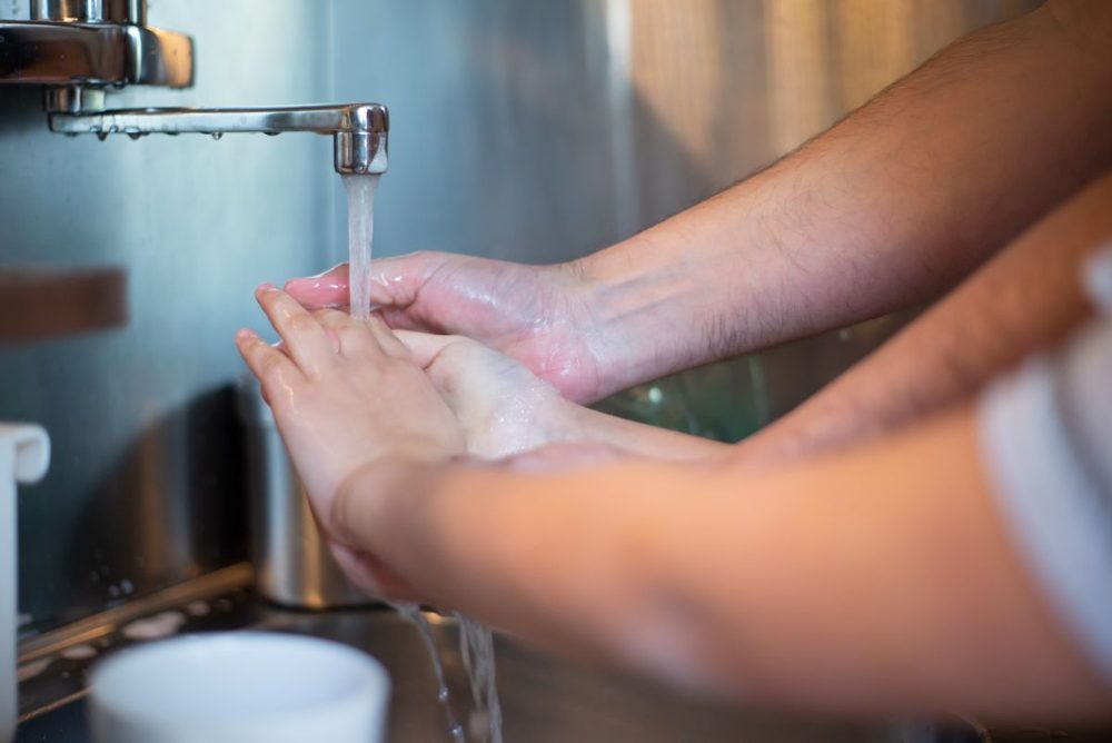 Family washing hands together in the kitchen