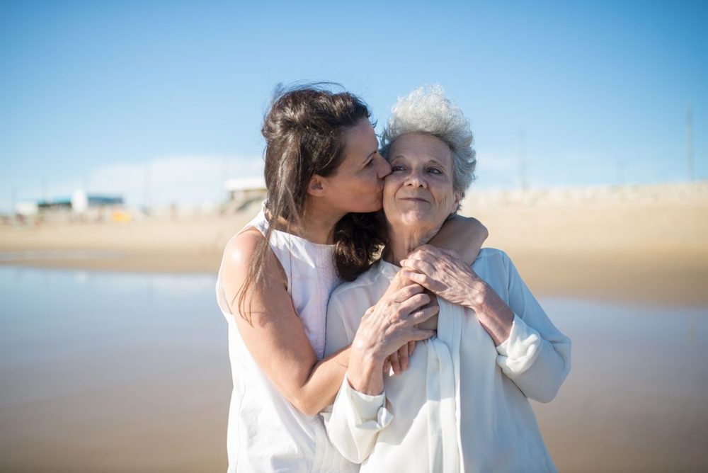 Adult daughter embracing her elderly mother warmly outdoors