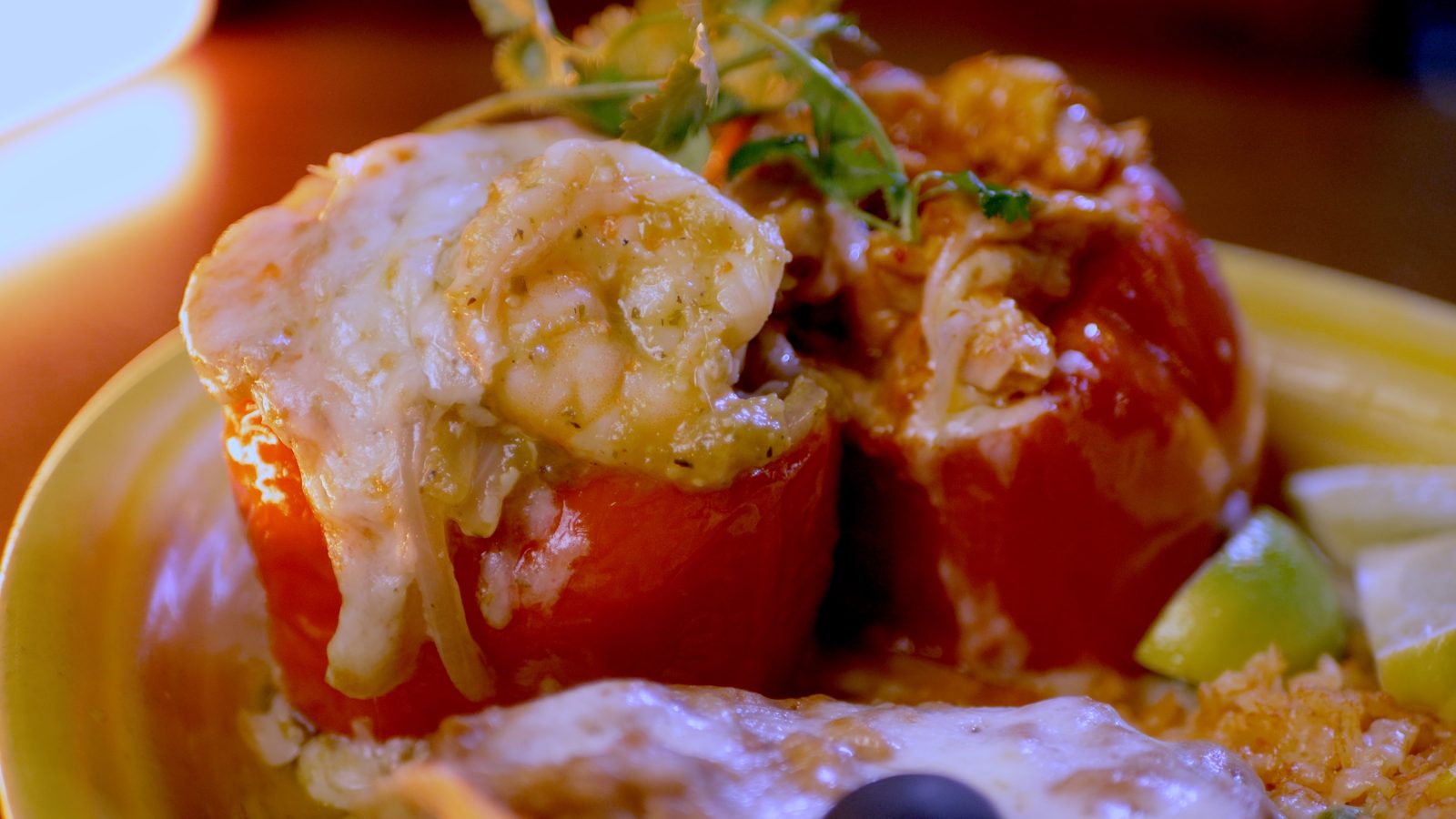 Spicy Chile Campana: stuffed red bell peppers with melted cheese, a lime wedge and black olive on a yellow plate at Casa de Bandini, Carlsbad