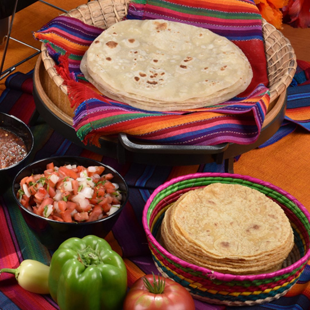 Baskets of homemade flour and corn tortillas on a striped serape with pico de gallo and fresh peppers at Casa de Bandini, Carlsbad