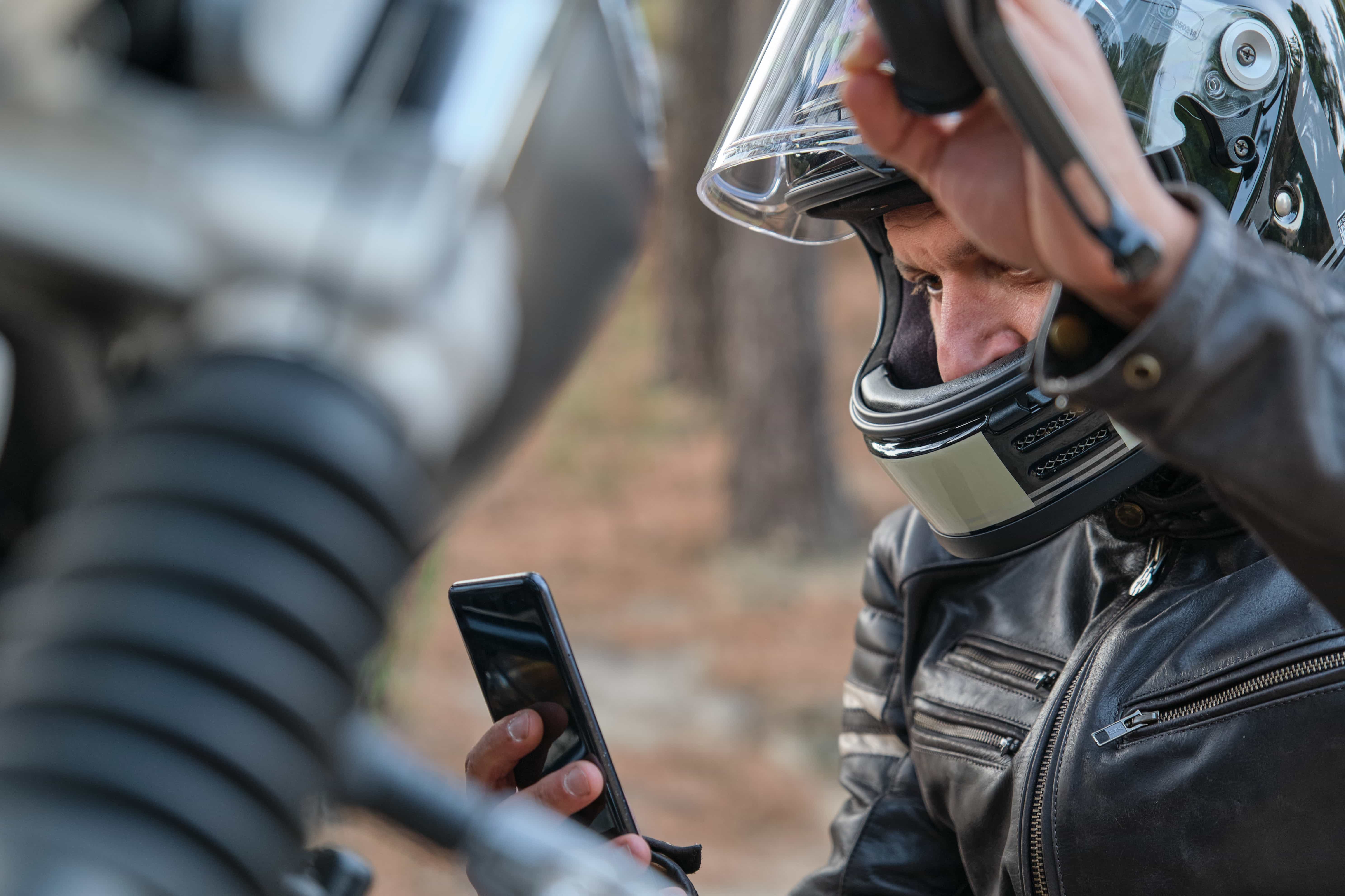 man with motorcycle looking at phone screen