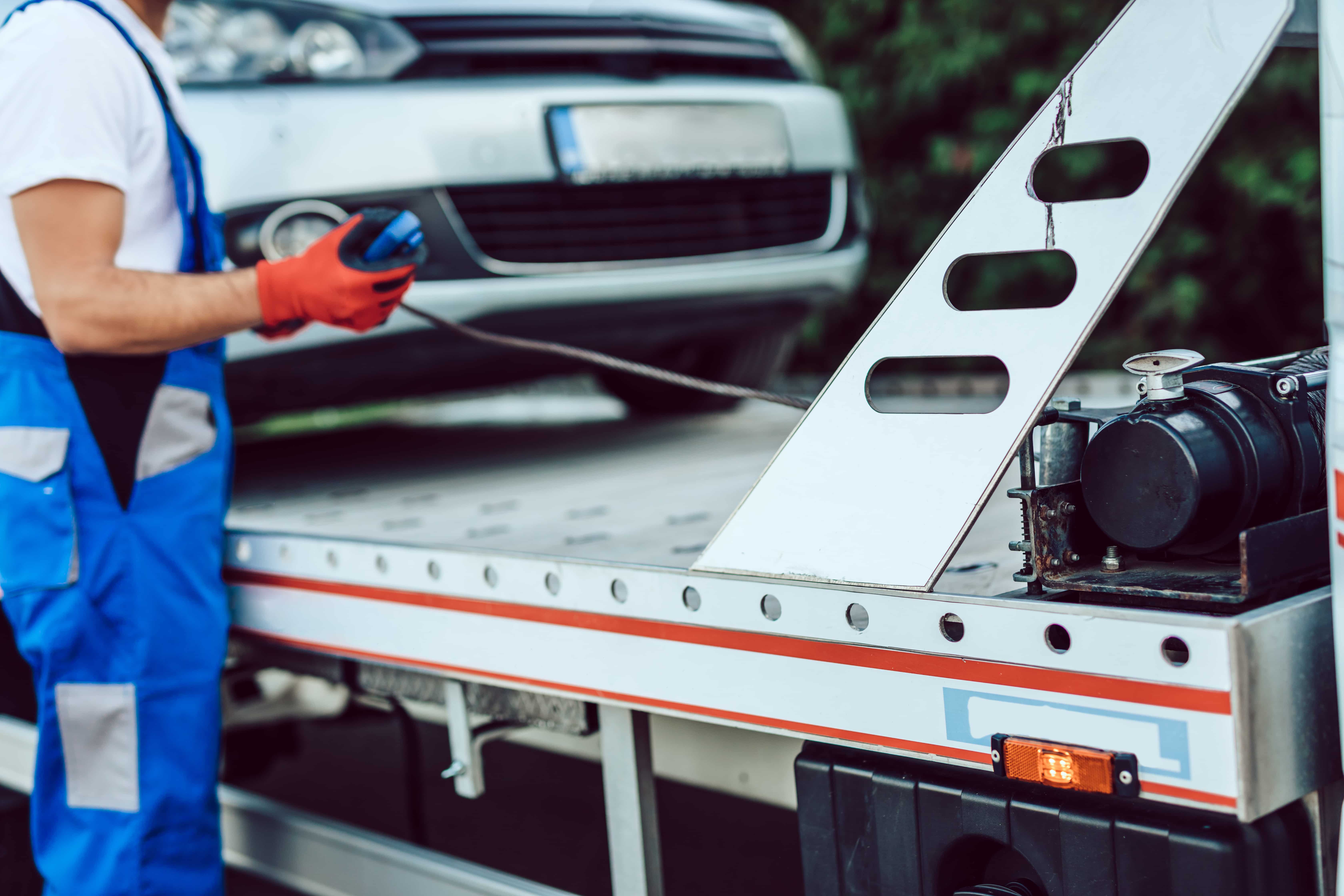 Male technician checking a car that is on a flatbed
