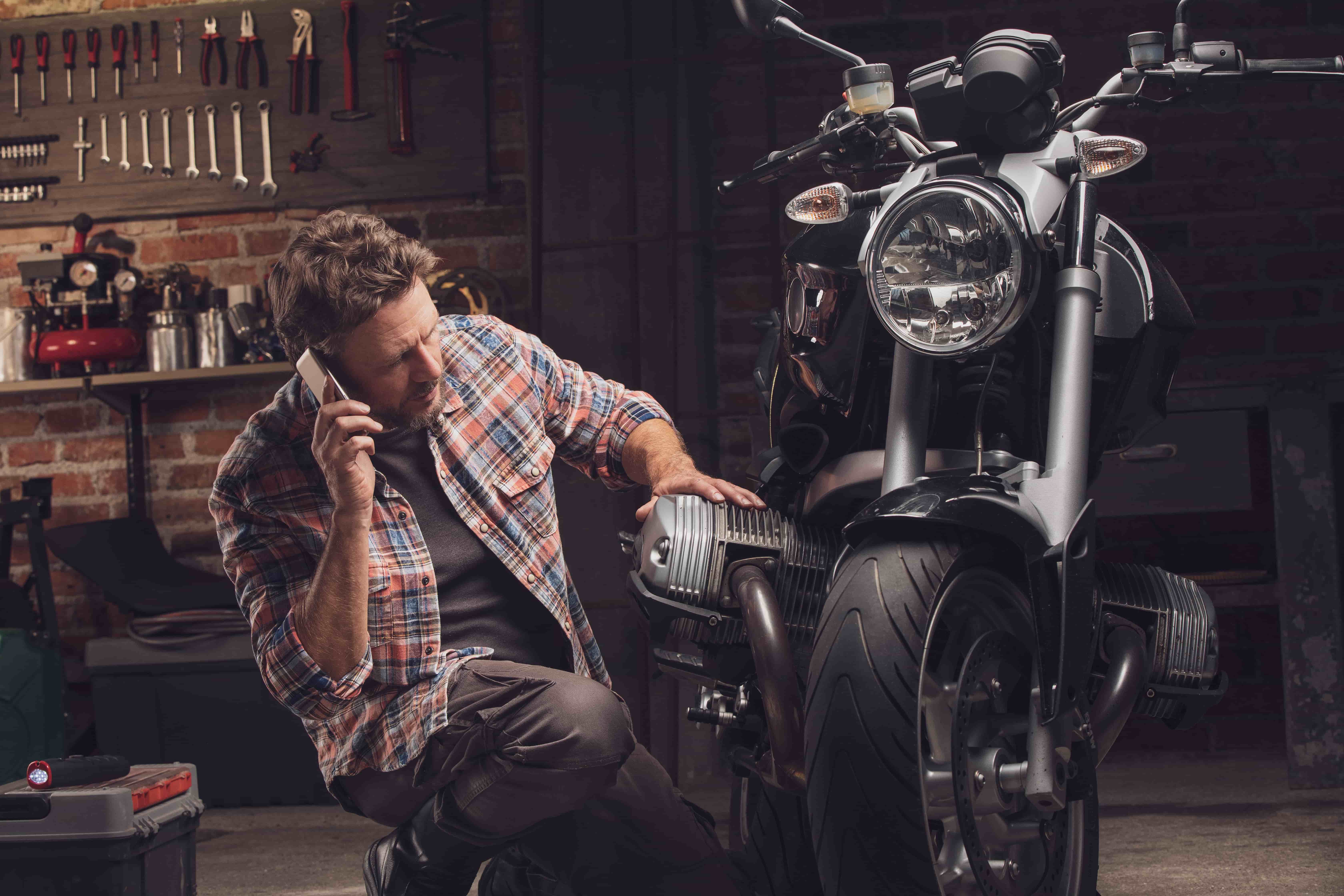 man in a garage on a call, kneeling next to his bike