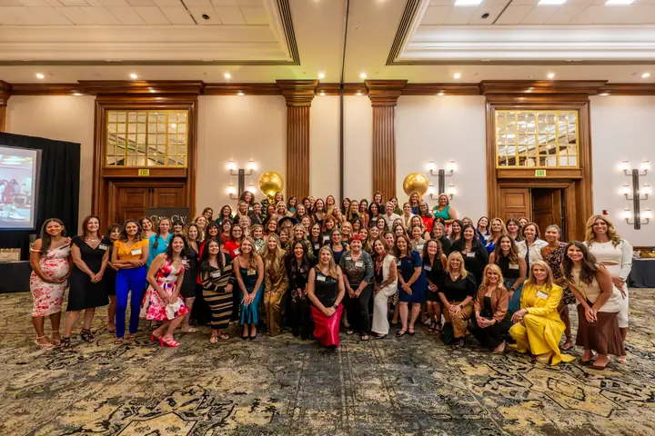 More than a hundred CWL members gathered together for a group photo in a ballroom