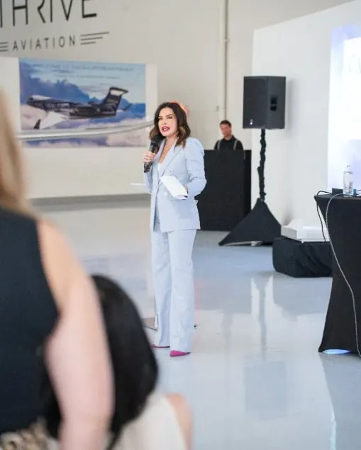Joyce Toti speaking to an audience inside the THRIVE Aviation hangar