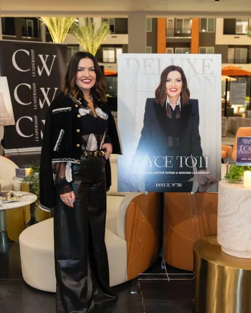 Joyce Toti standing beside her Deluxe Version magazine cover, Issue No. 30, at a CWL event