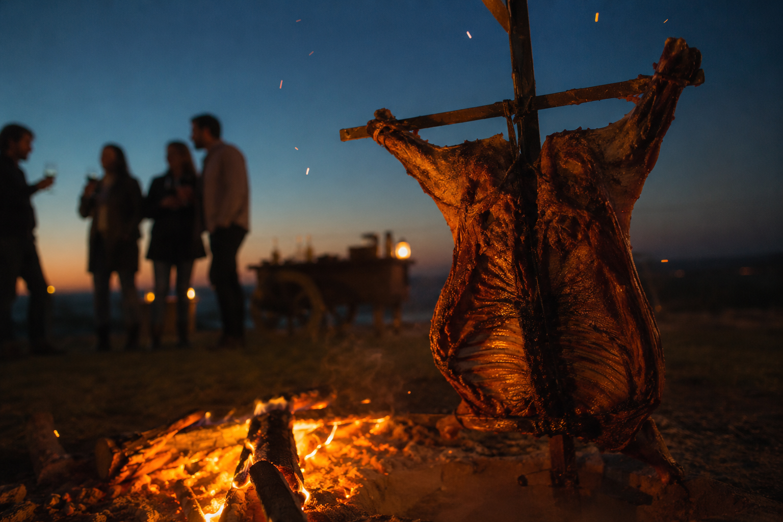 Asador a la cruz al atardecer con amigos conversando alrededor del fuego