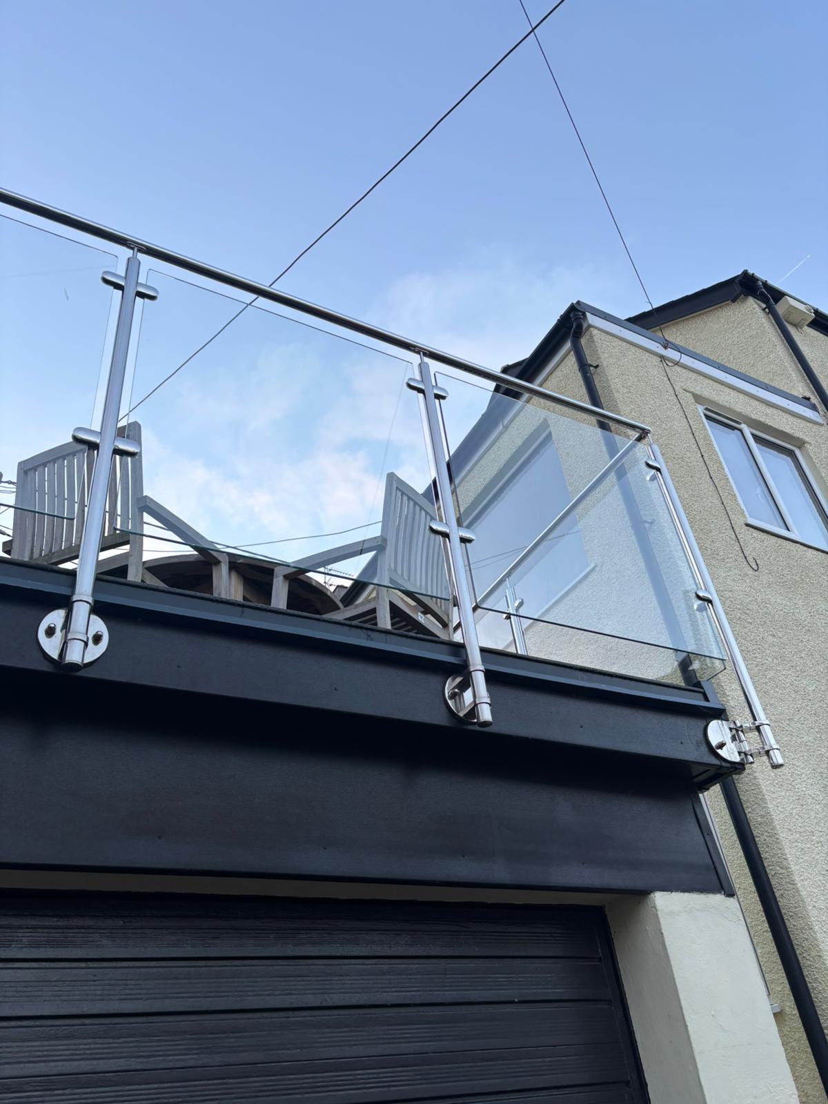 Glass balustrade with stainless steel posts installed on raised terrace in Anglesey