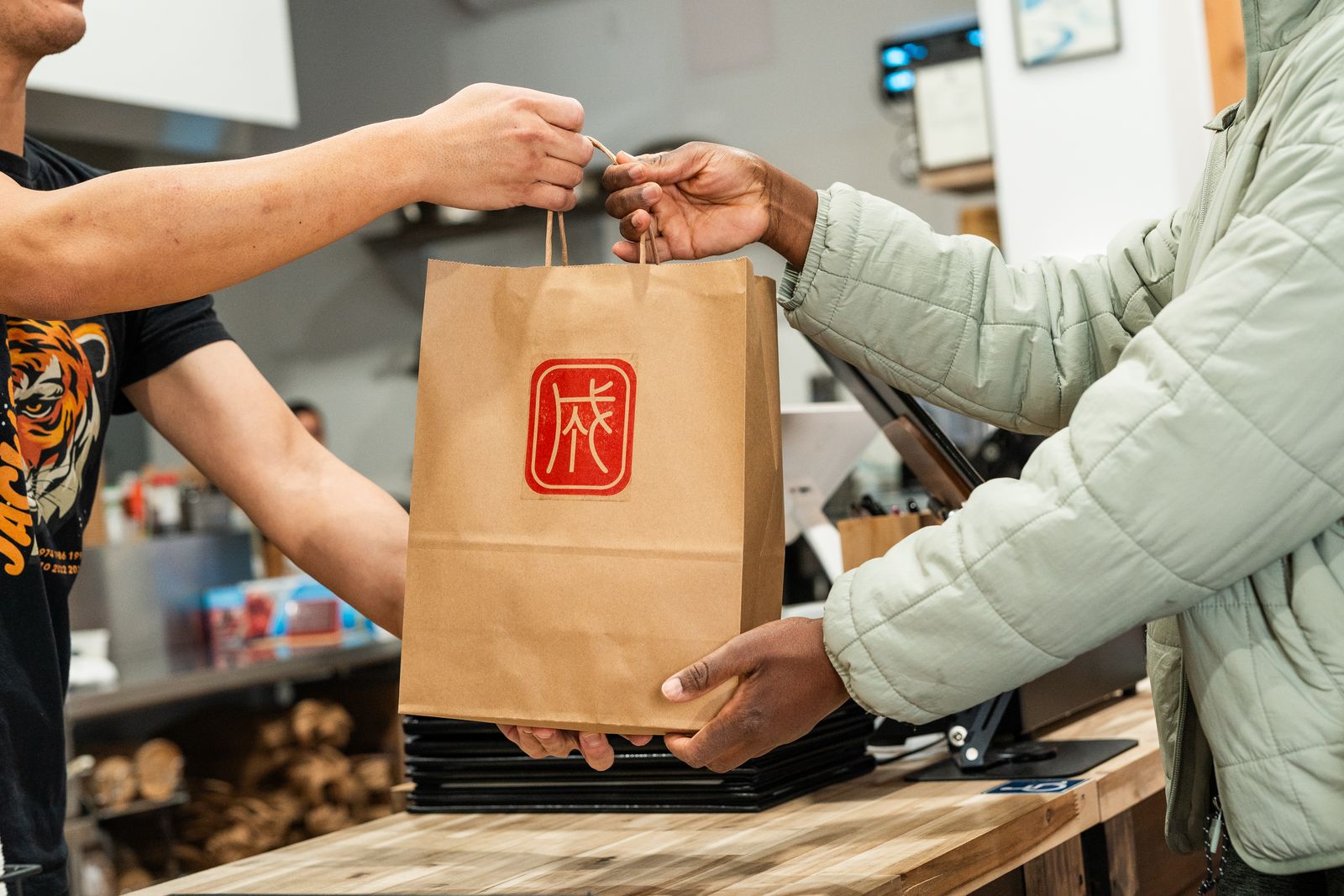 Staff handing a takeout bag to a guest