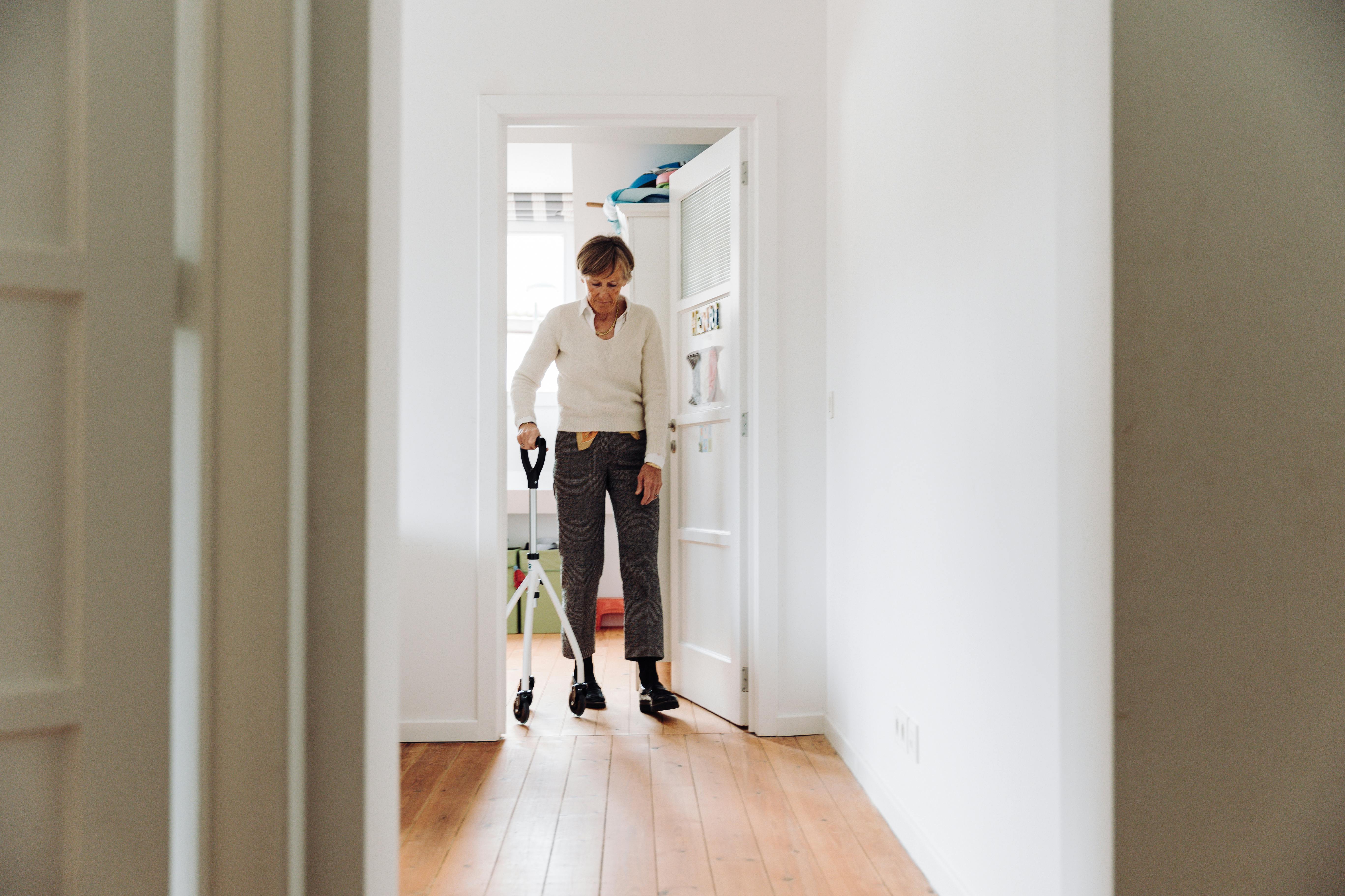 “Elderly woman using walker at home, senior maintaining mobility and independence while walking through a bright hallway.” “Elderly woman using walker at home, senior maintaining mobility and independence while walking through a bright hallway.”