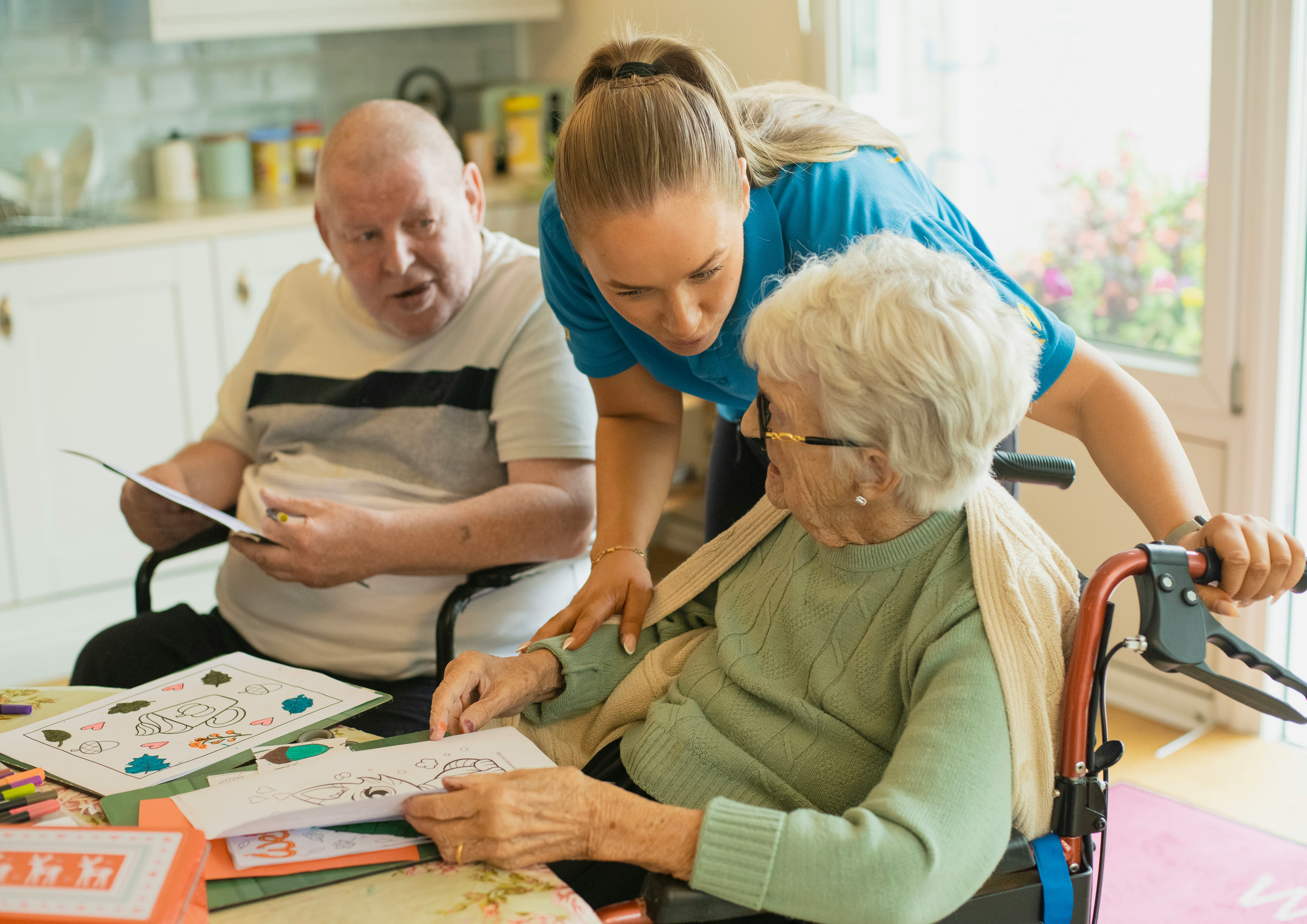 Care Worker assisting a sitting elderly woman as she is doing mental exercises on pieces of paper. Care Worker assisting a sitting elderly woman as she is doing mental exercises on pieces of paper.