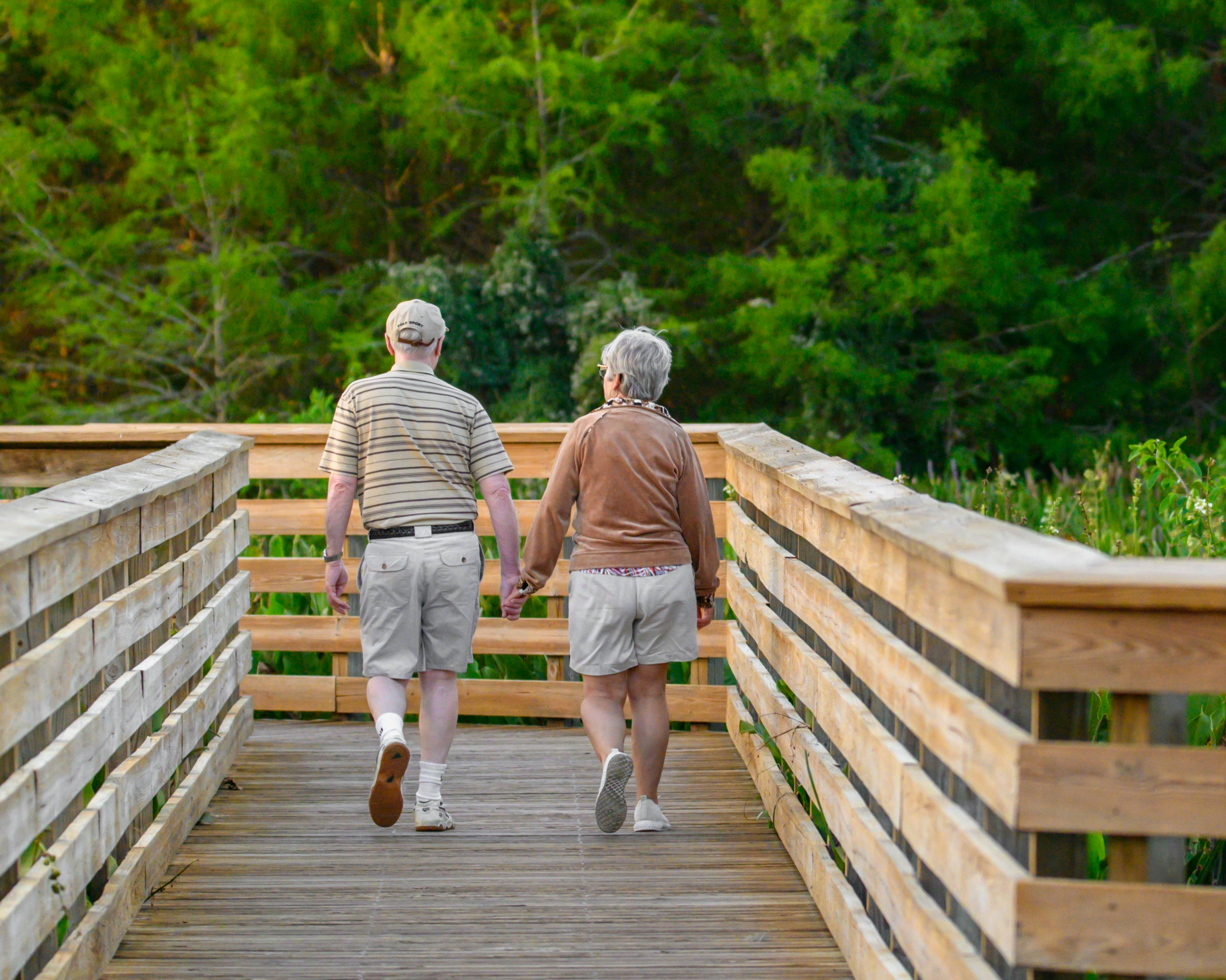 Two elderly people walking alongside each other on a bridge Two elderly people walking alongside each other on a bridge