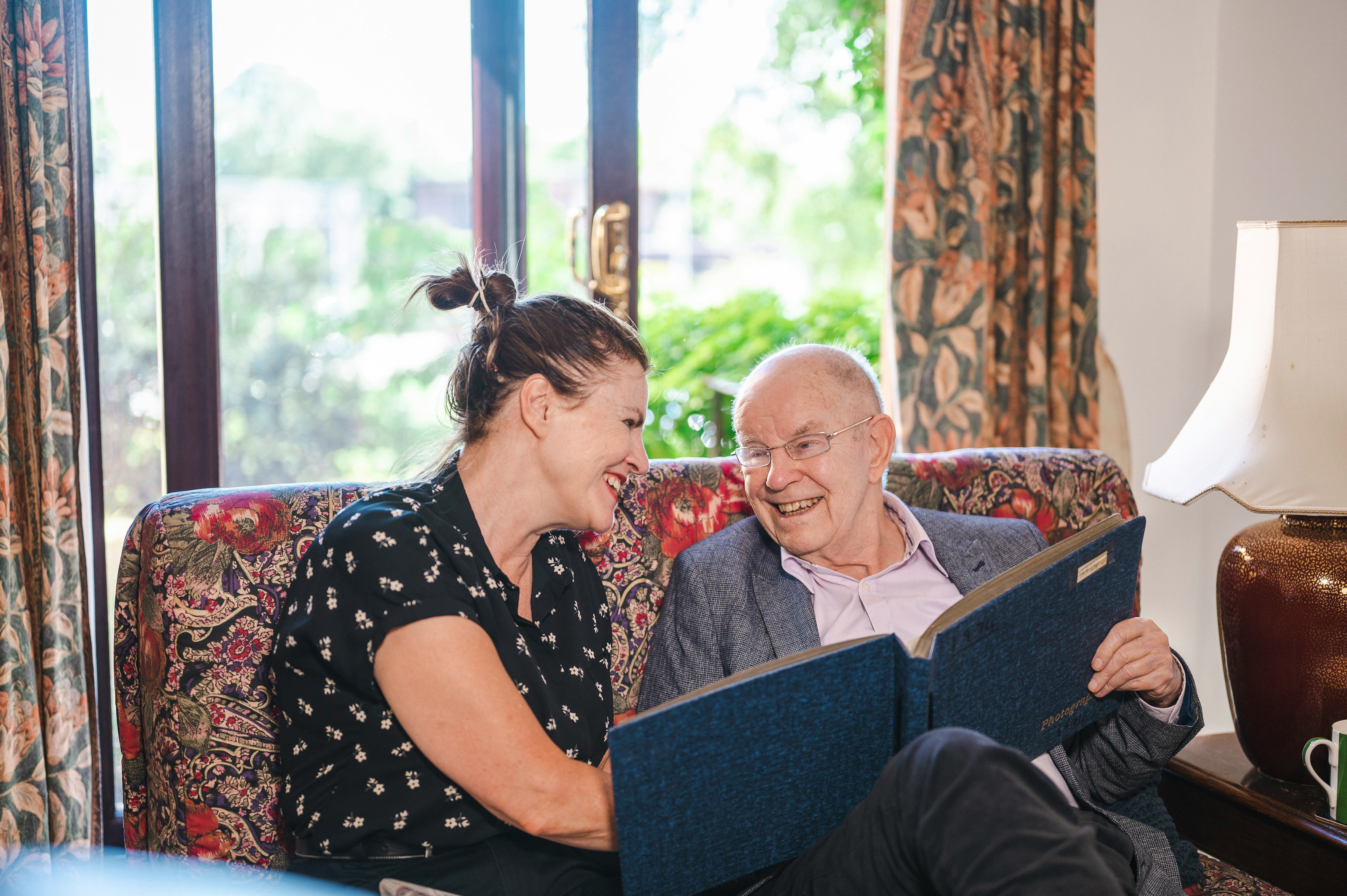 Daughter and elderly father looking at memory book Daughter and elderly father looking at memory book