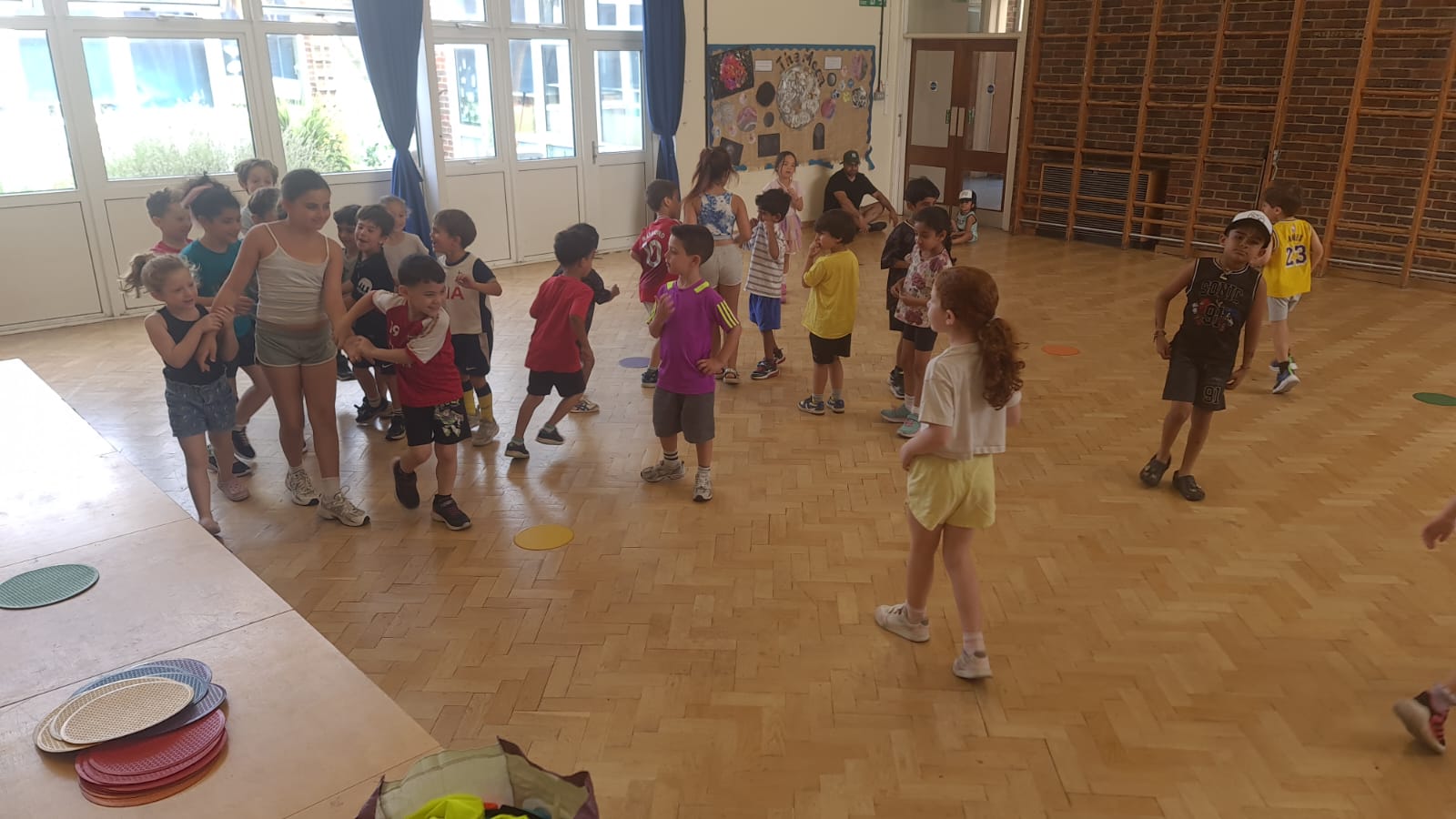A large group of children mid-game at a Mad4Sports session in a North London school hall