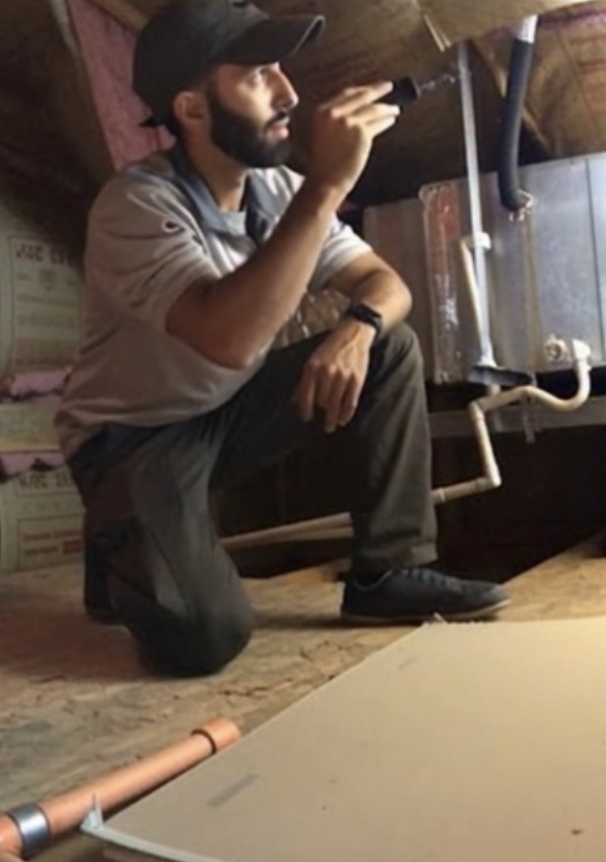 Konnor Kirkwood inspecting an attic system with a flashlight