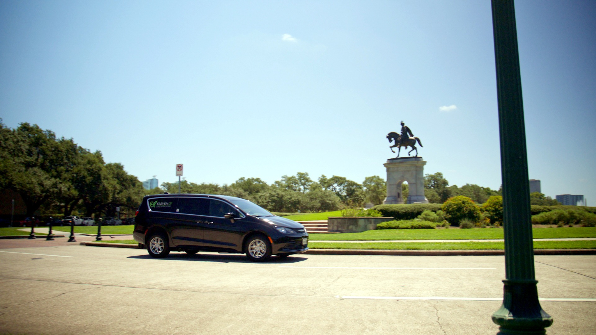 Branded ElevenO3 vehicle traveling past a Houston landmark