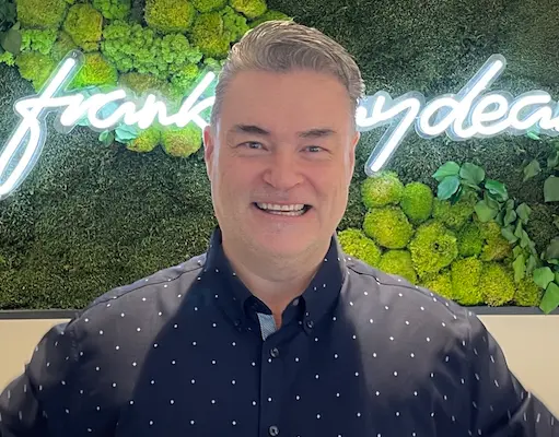 Smiling business leader representing the CEO of My Business Automated, standing in front of company branding.