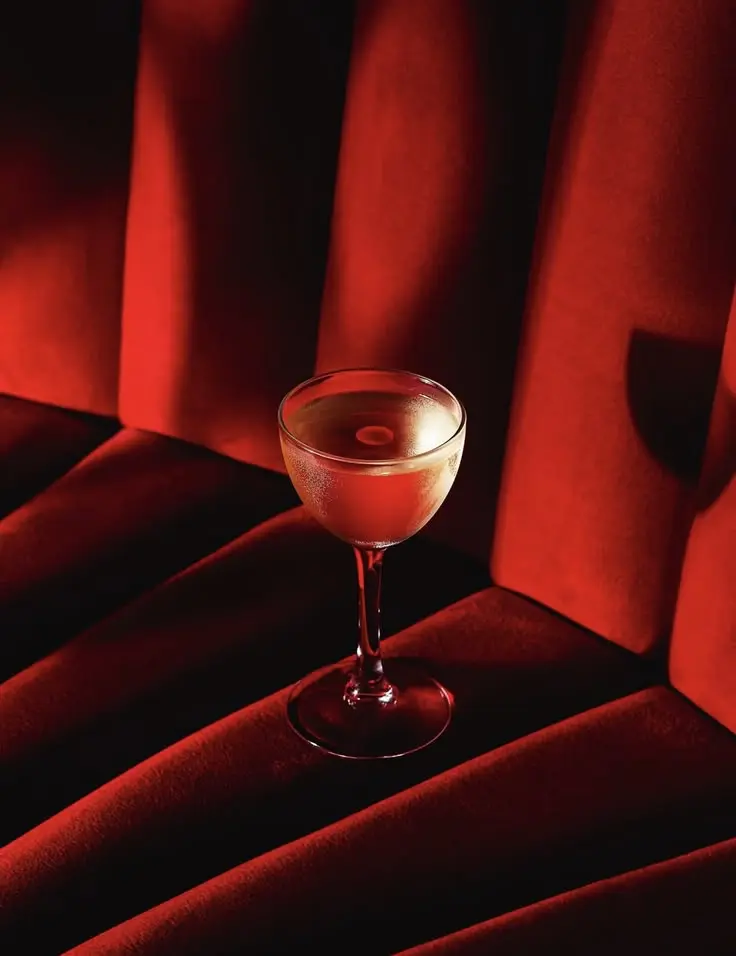 A coupe glass on a red velvet banquette