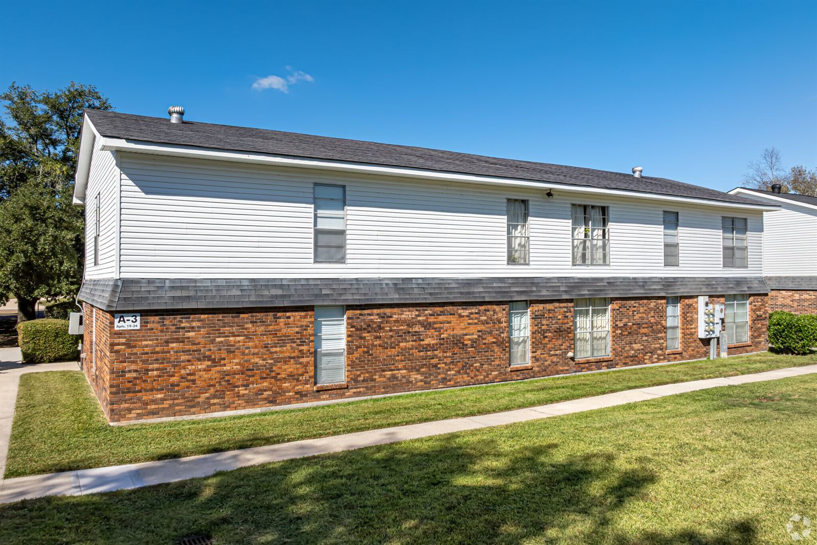 Two-story brick and white-sided apartment building with a lawn
