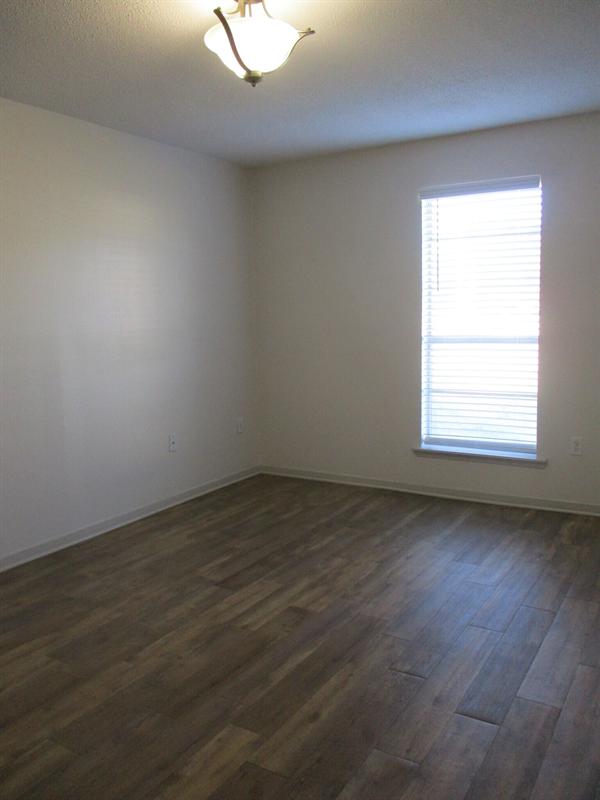 Renovated bedroom with new plank flooring and a window