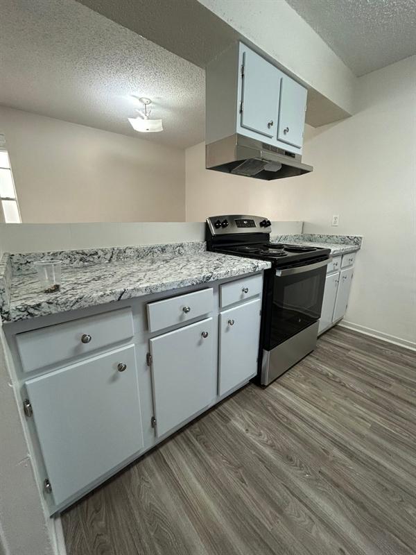 Renovated kitchen with new countertops, white cabinets and a stainless range