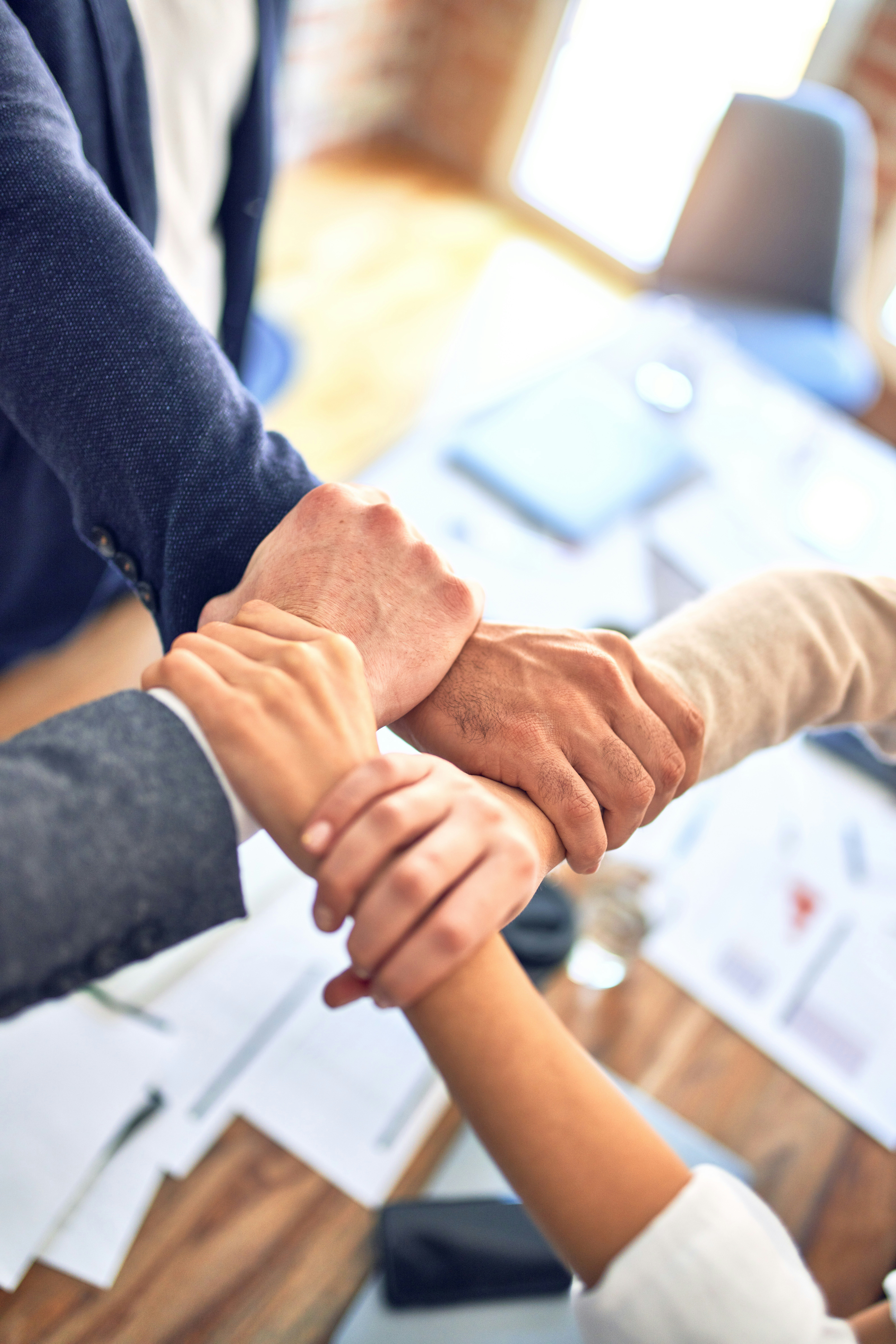 Equipo uniendo manos sobre la mesa de trabajo