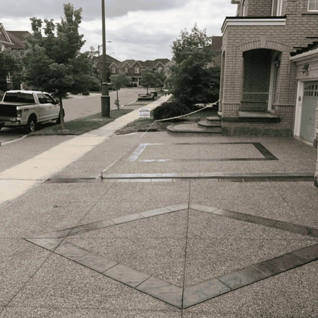 Wide exposed aggregate concrete driveway in front of a home