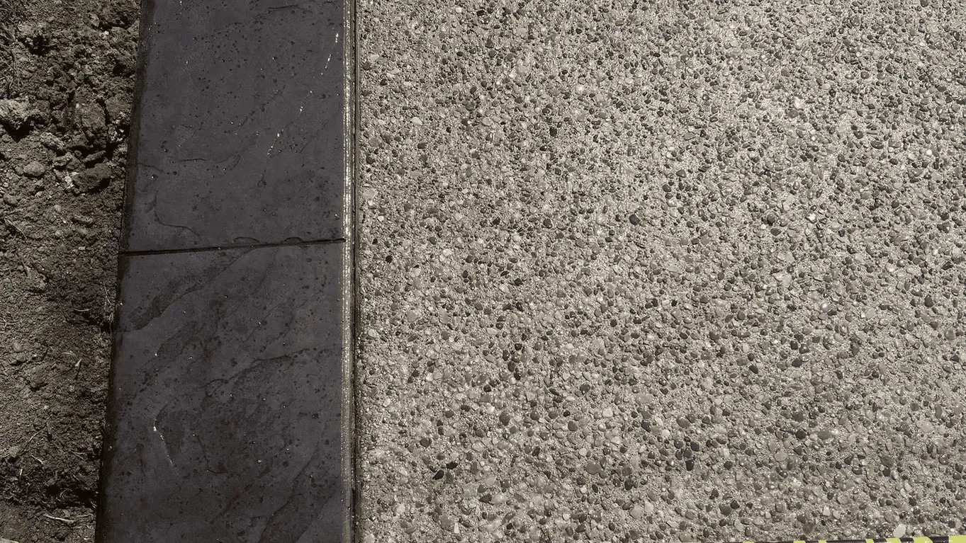Close view of exposed aggregate concrete beside a dark border