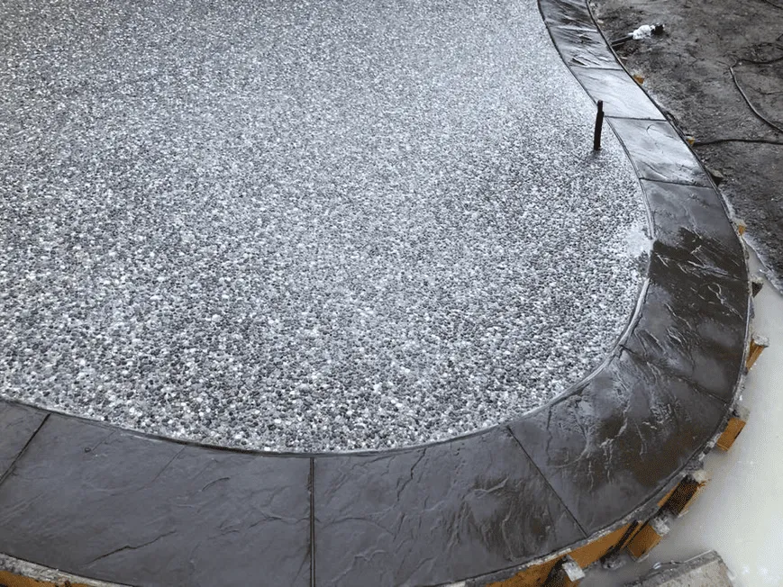 Close view of a curved exposed aggregate walkway and black border