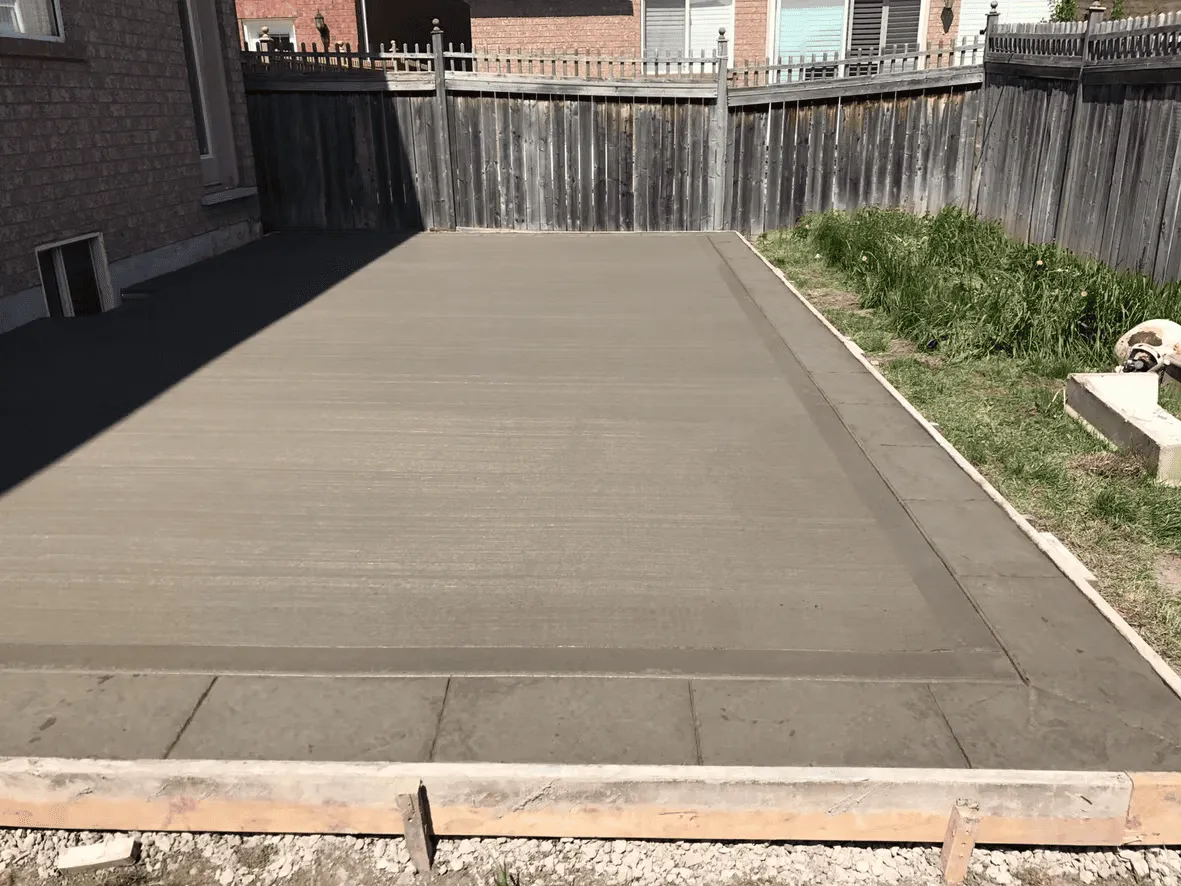 Finished plain concrete patio beside a brick home