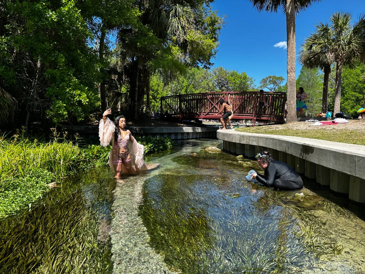 A client posing in a ruffled robe while Beatrice shoots from the water