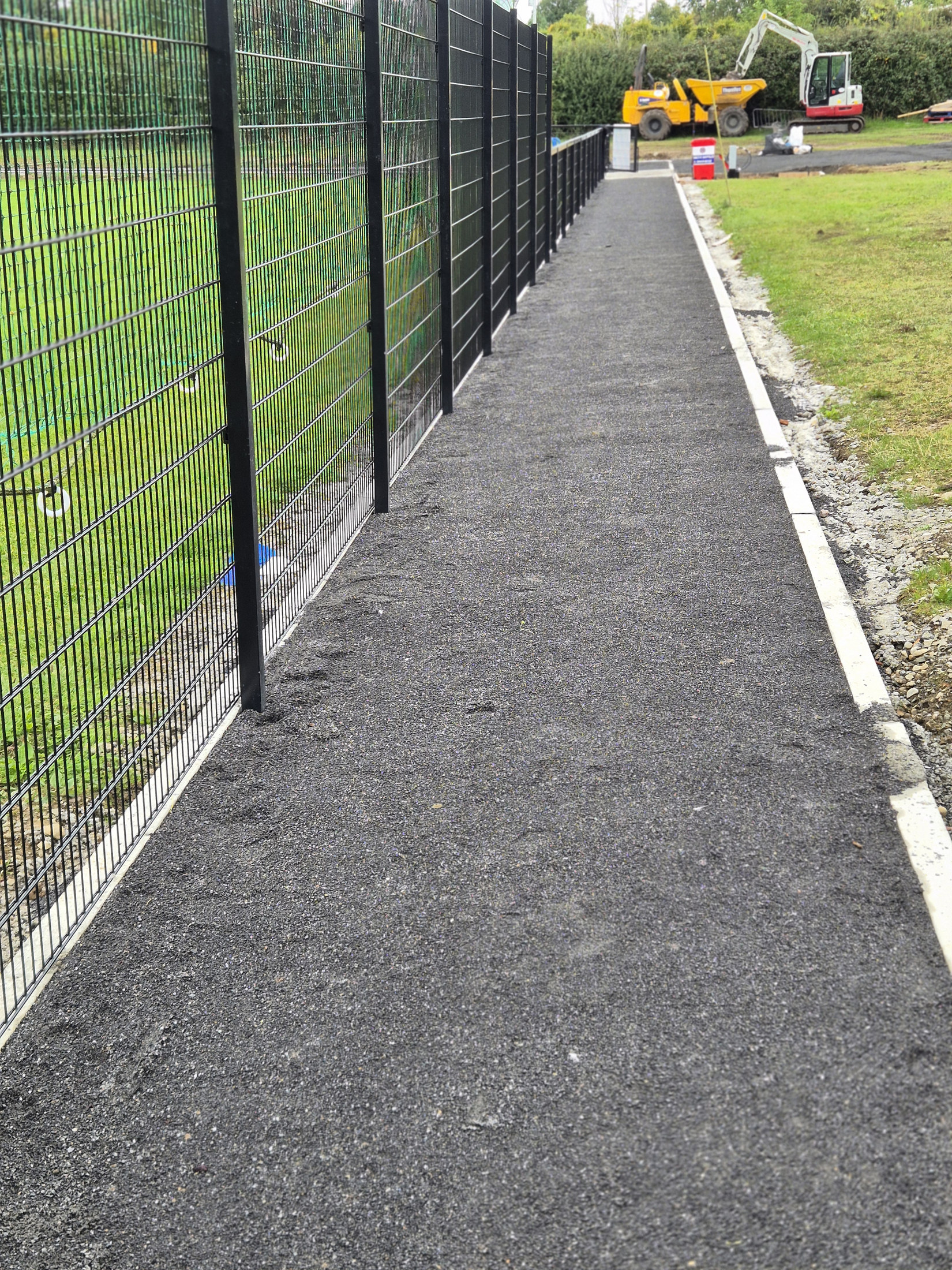 Asphalt path leading towards the end of the fence
