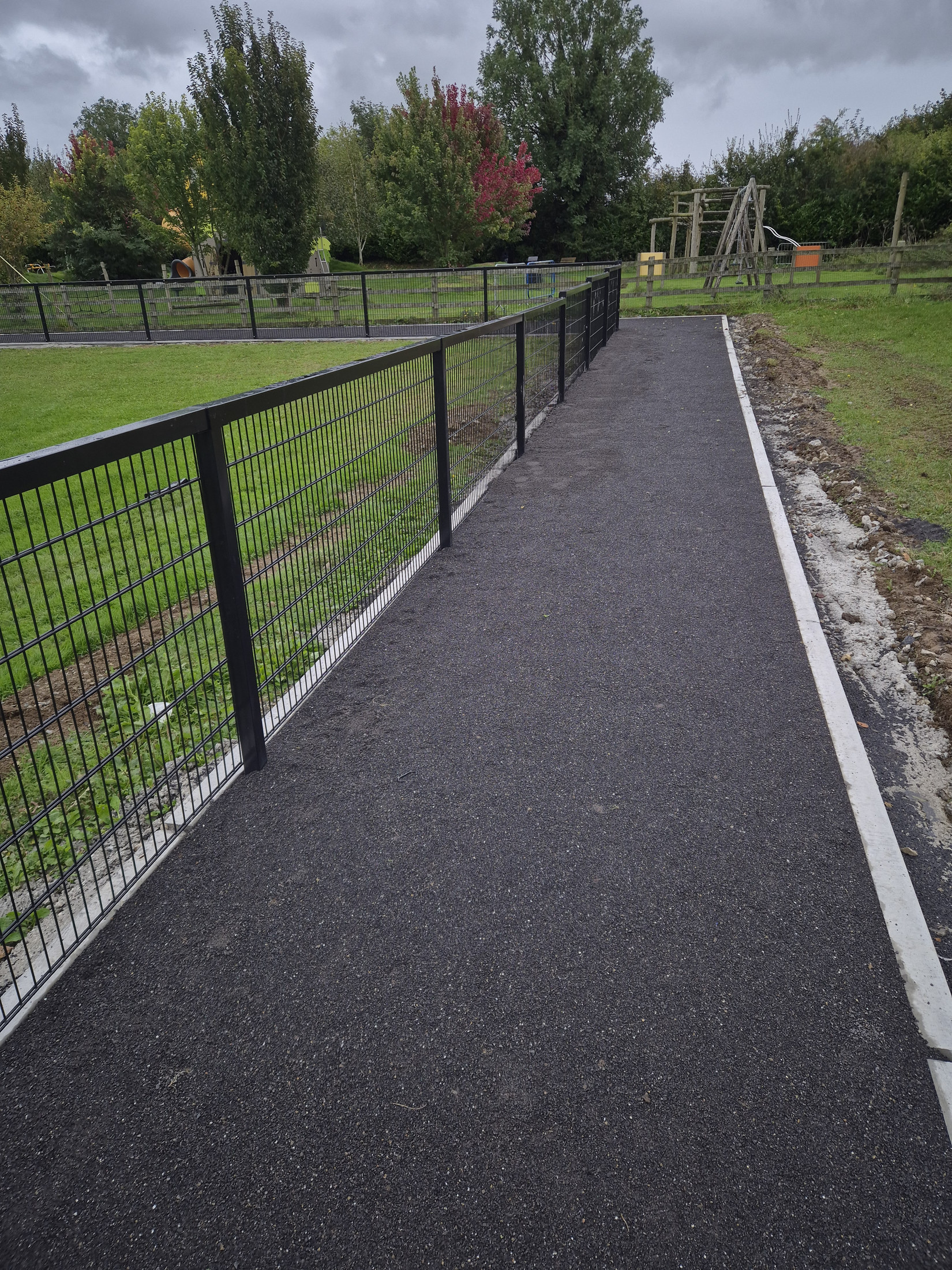 Finished asphalt path beside the fence