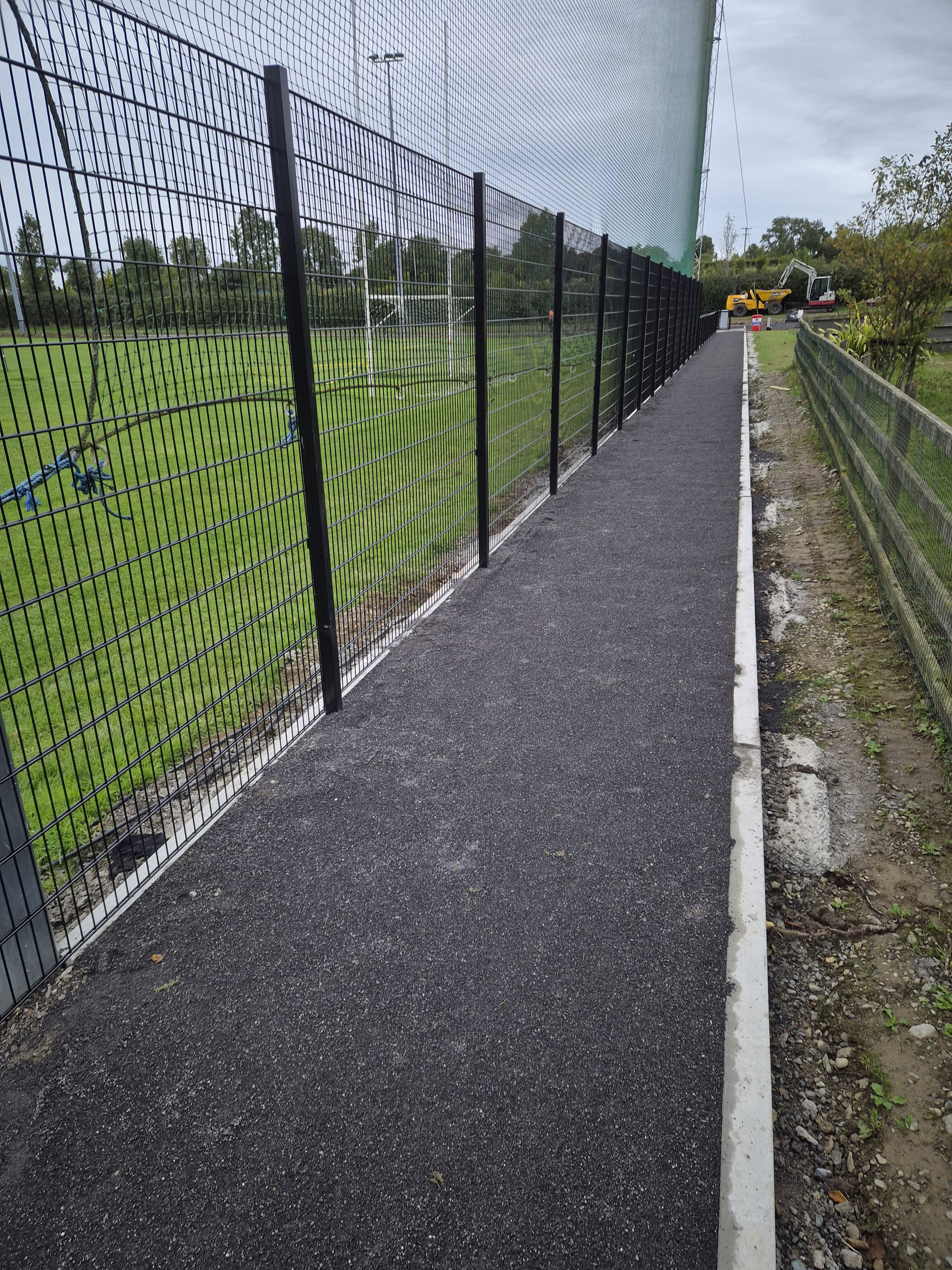 Finished asphalt path along tall mesh fencing