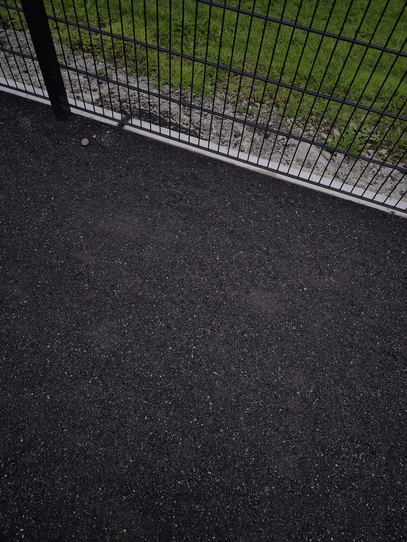 Asphalt path beside the mesh fence