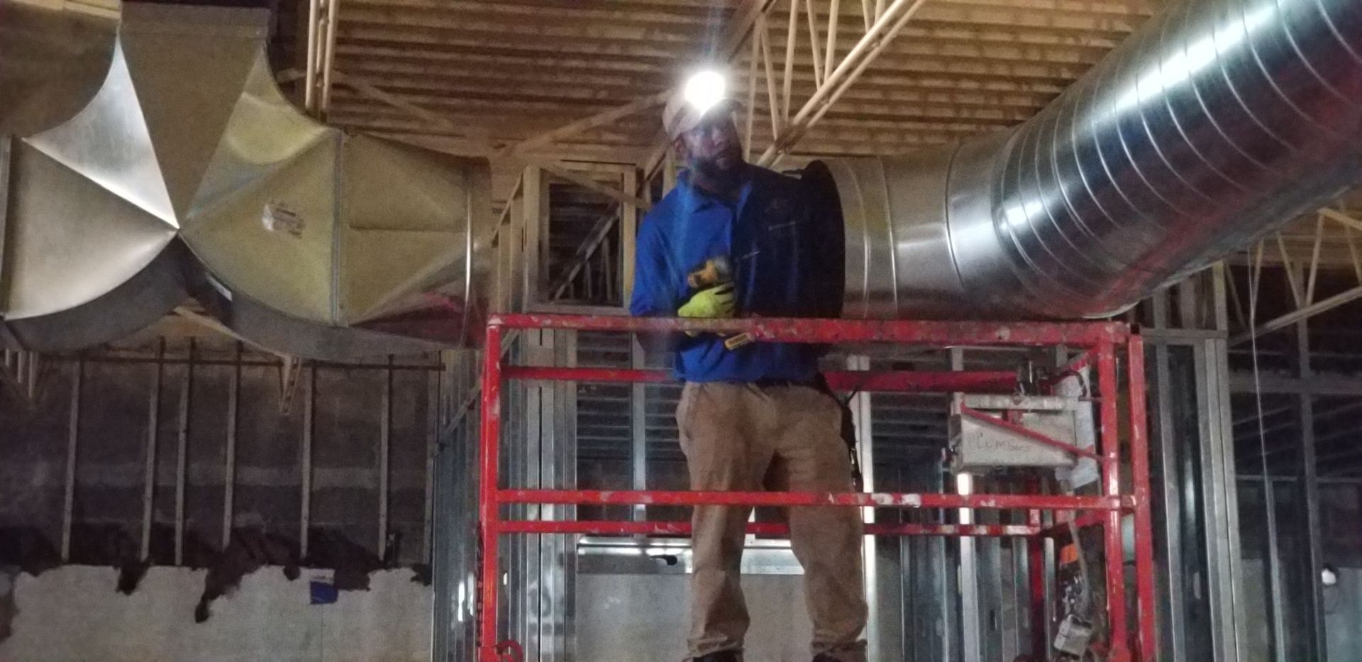 Technician working from a lift on commercial ventilation ductwork